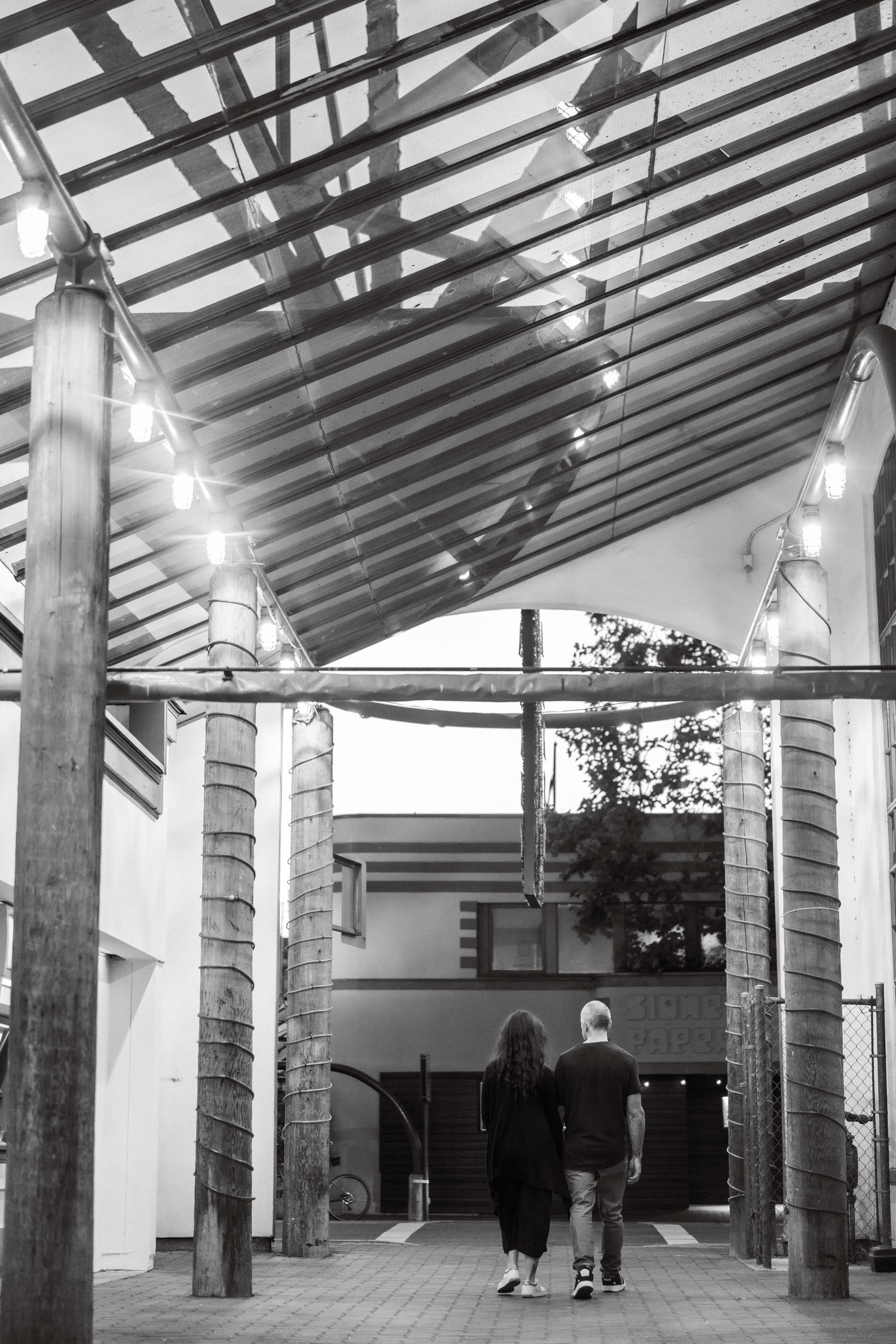 Modern covered walkway with geometric pillars and lighting creating parallel lines.