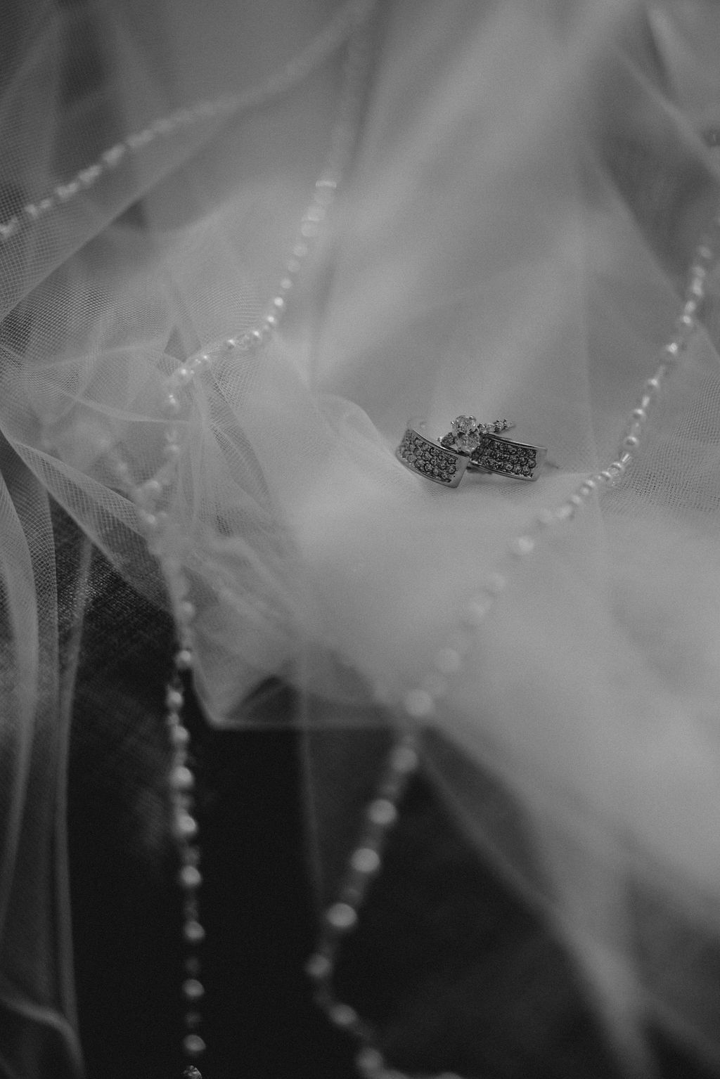 Delicate white tulle veil with pearl details shimmering in soft light.
