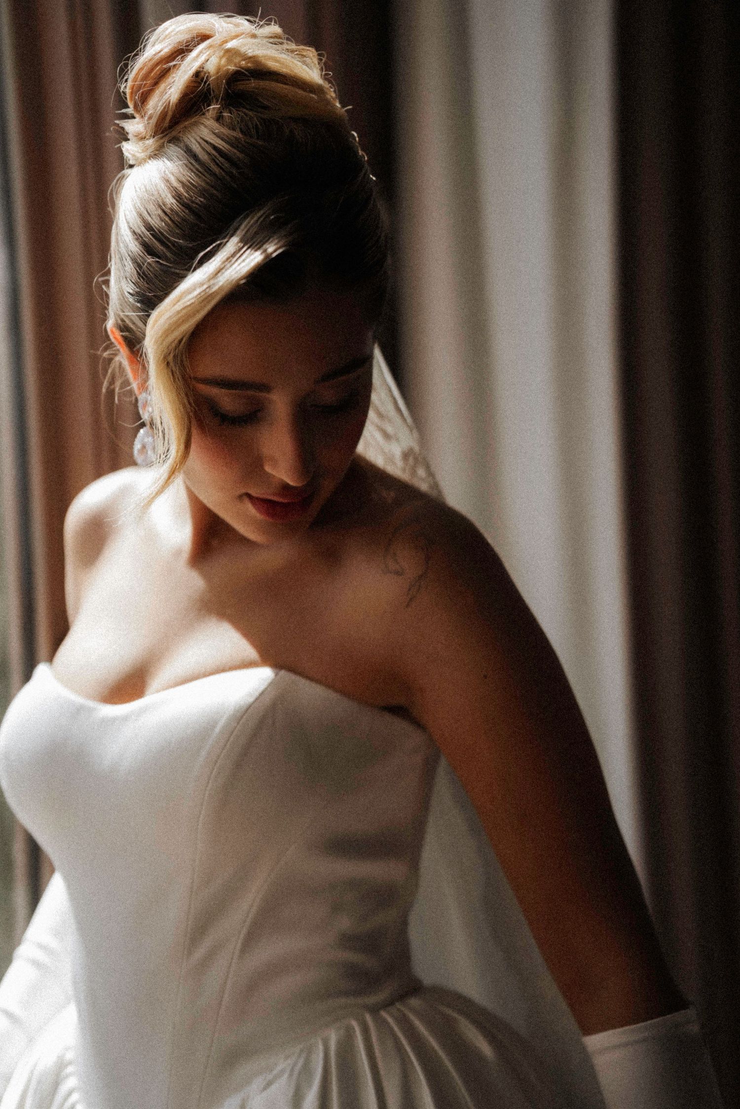 A series of five soft and romantic bridal photos showing a woman in a white wedding gown gazing downward by a window.