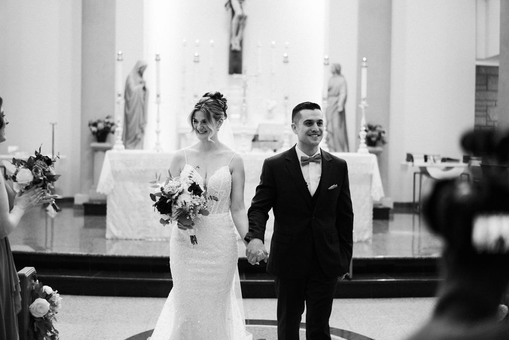 Black and white wedding ceremony photos inside an elegant venue with white columns.