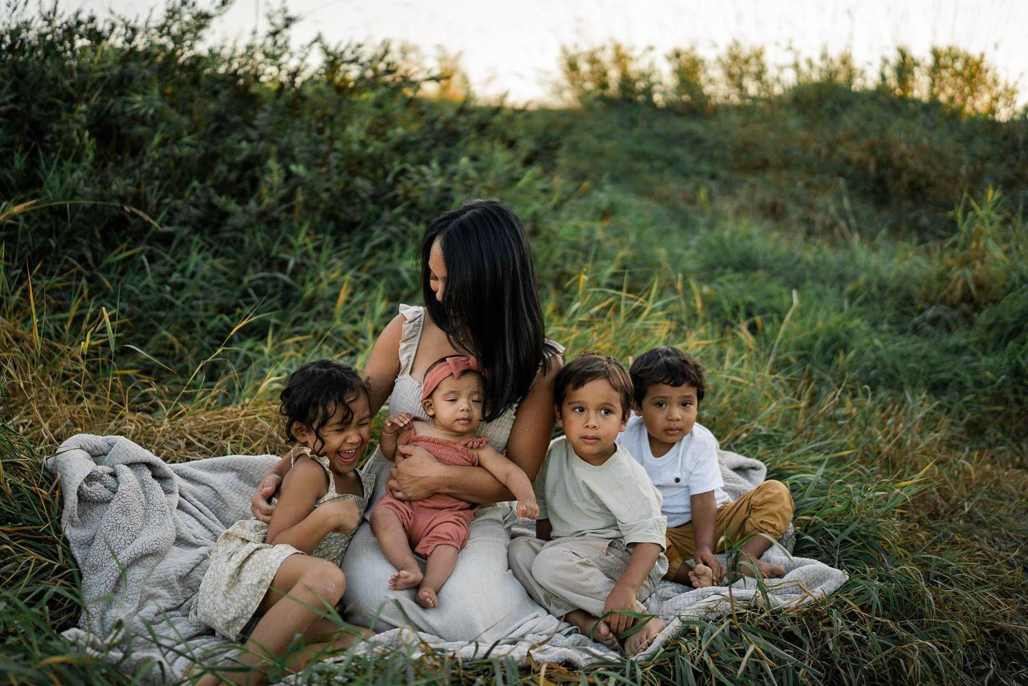Family having a relaxing picnic outdoors on a blanket during sunset.
