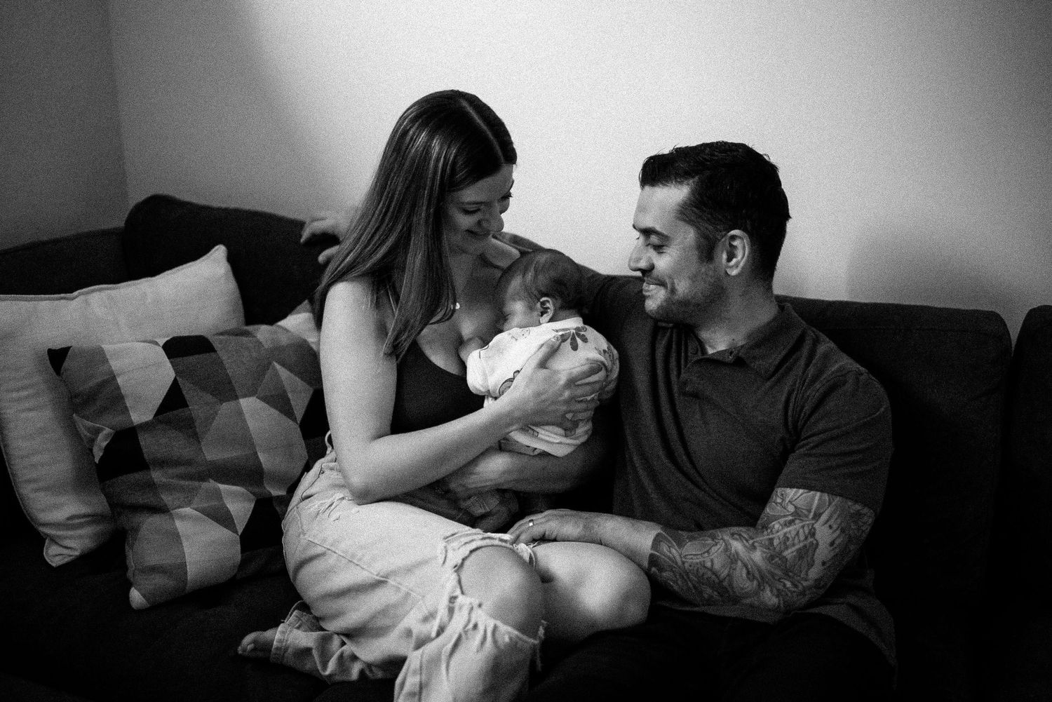 A series of black and white photos showing tender moments between parents and their newborn baby at home.