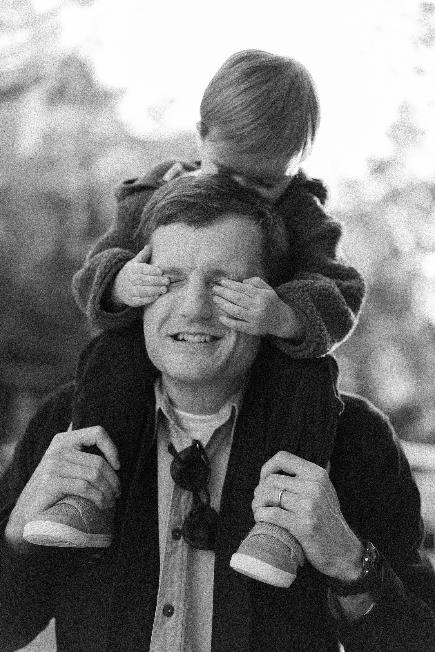 Playful black and white moment with hands covering eyes in natural light.