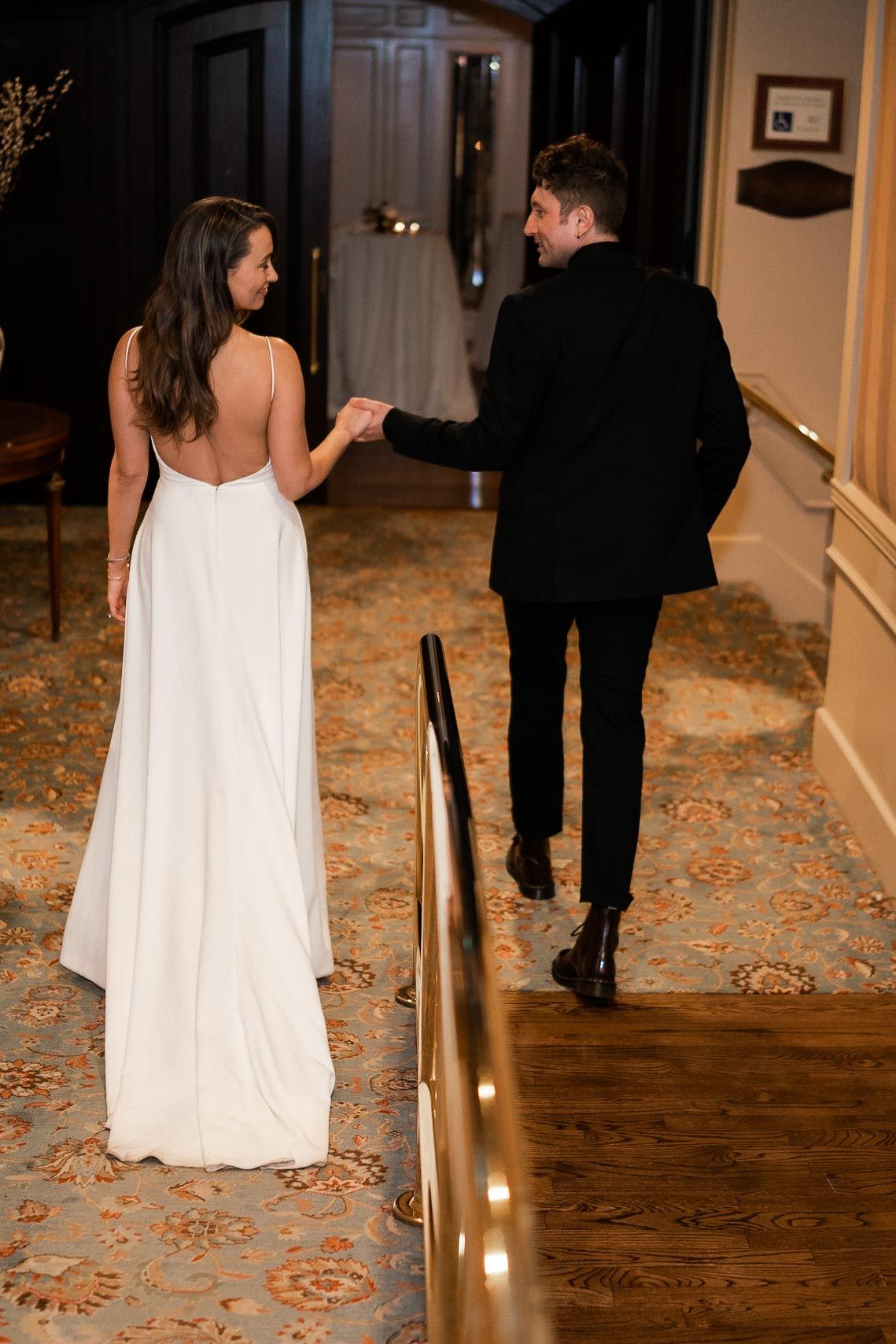 Couple walking down a hallway with ornate carpeting and elegant lighting.