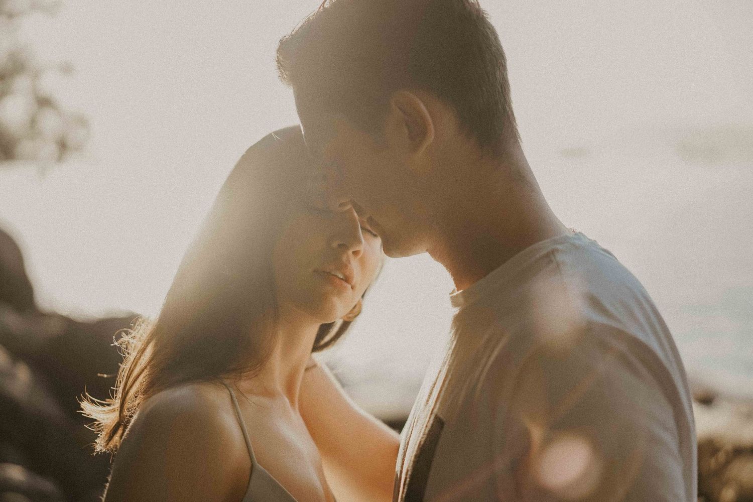 Intimate silhouette photo of couple against glowing sunset sky.