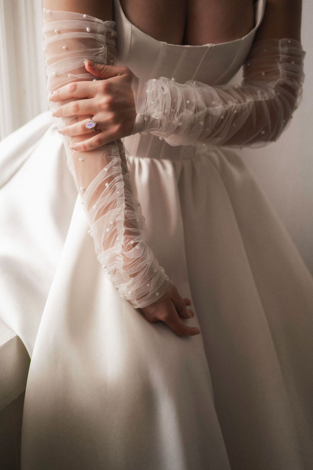 Close-up details of a classic white wedding dress with delicate lace sleeves.