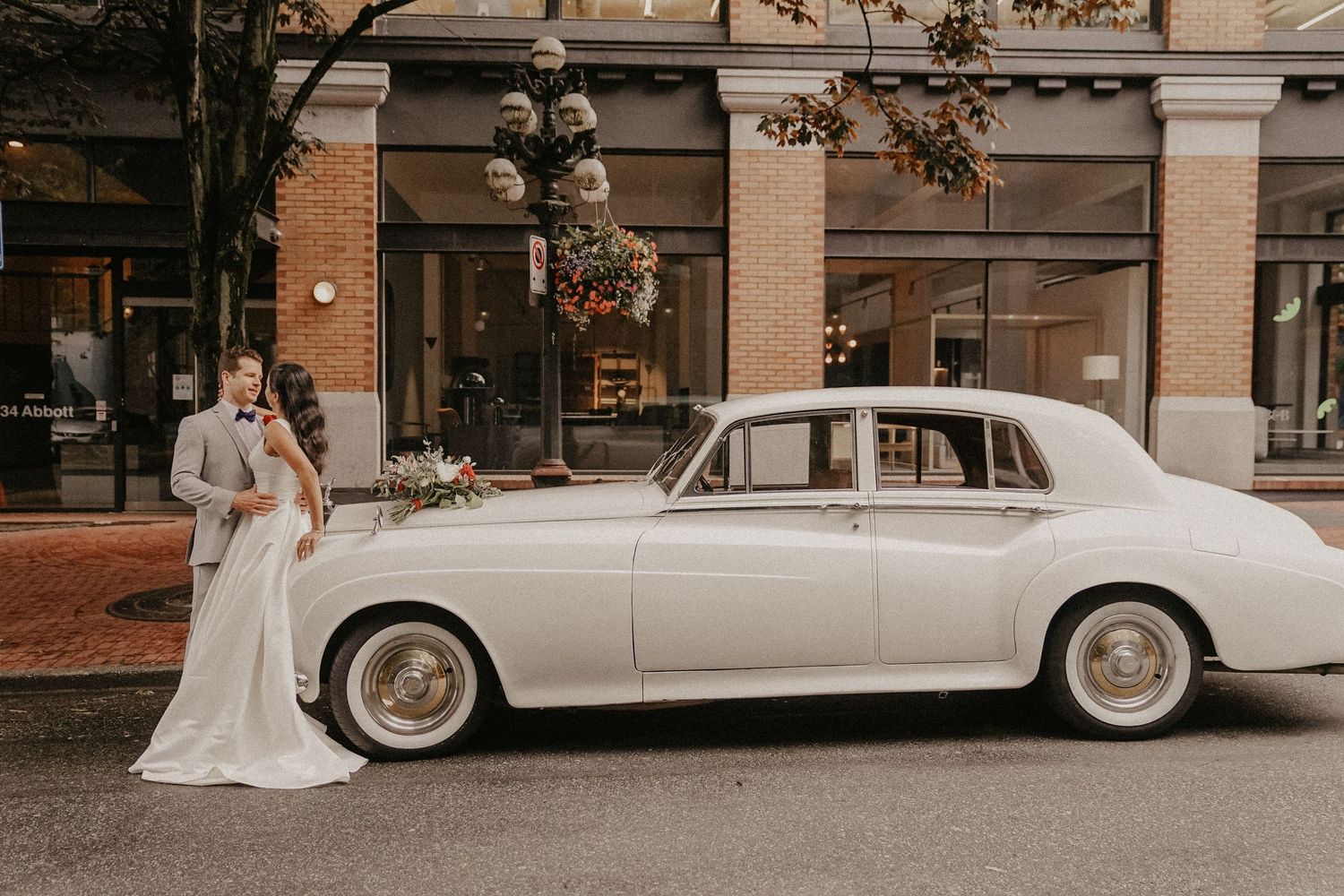 Classic white vintage wedding car parked outside urban buildings.