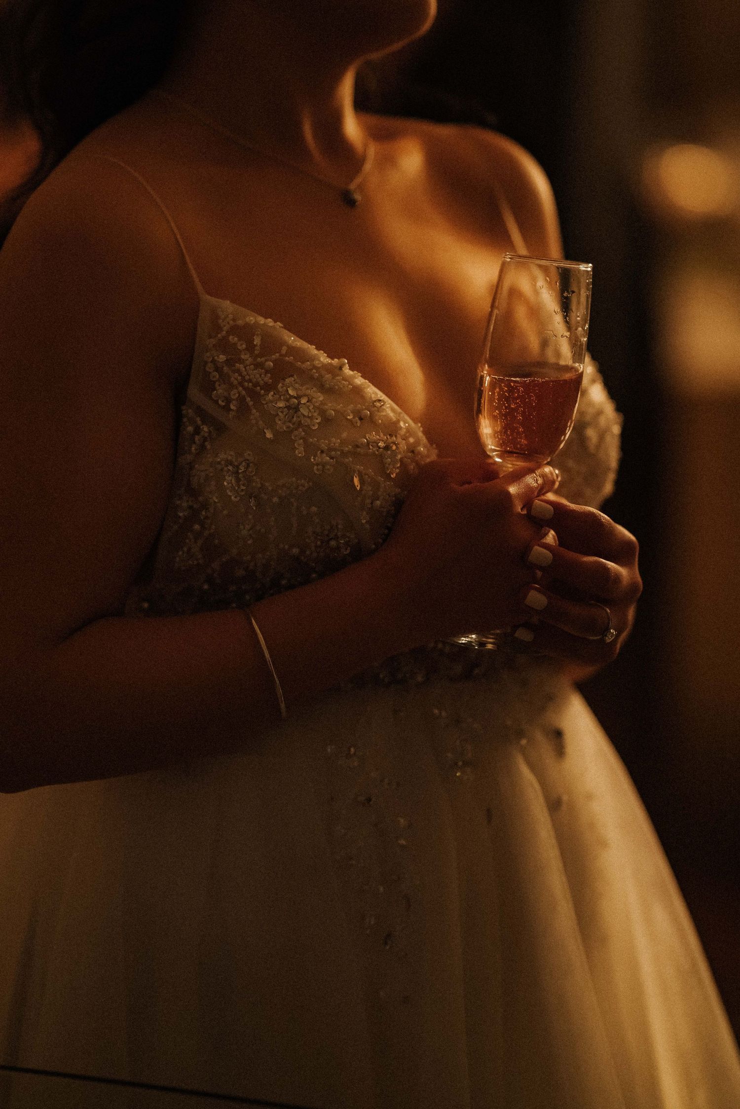 Detail shots of an elegant lace wedding dress in warm ambient lighting.