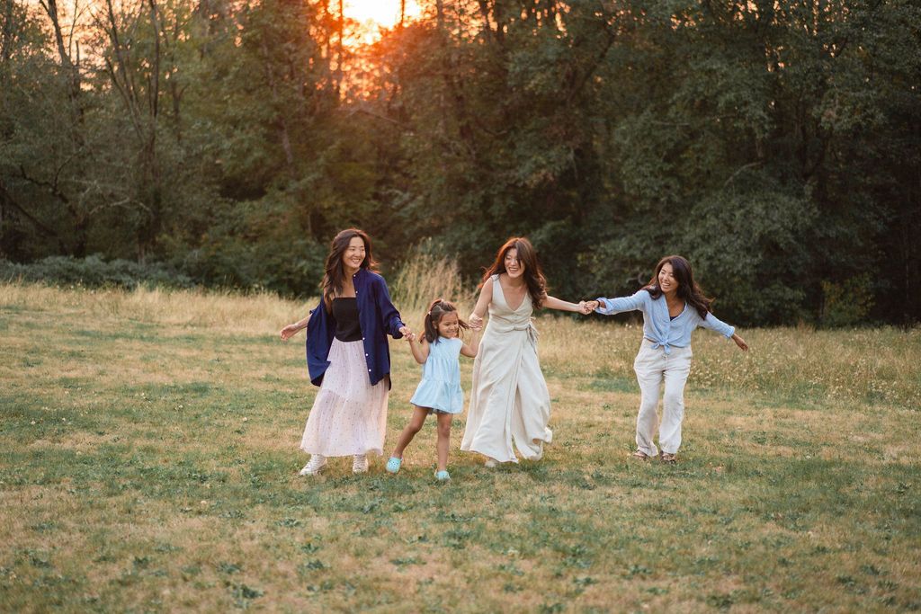 Group relaxing together on grassy hill during golden hour sunset.