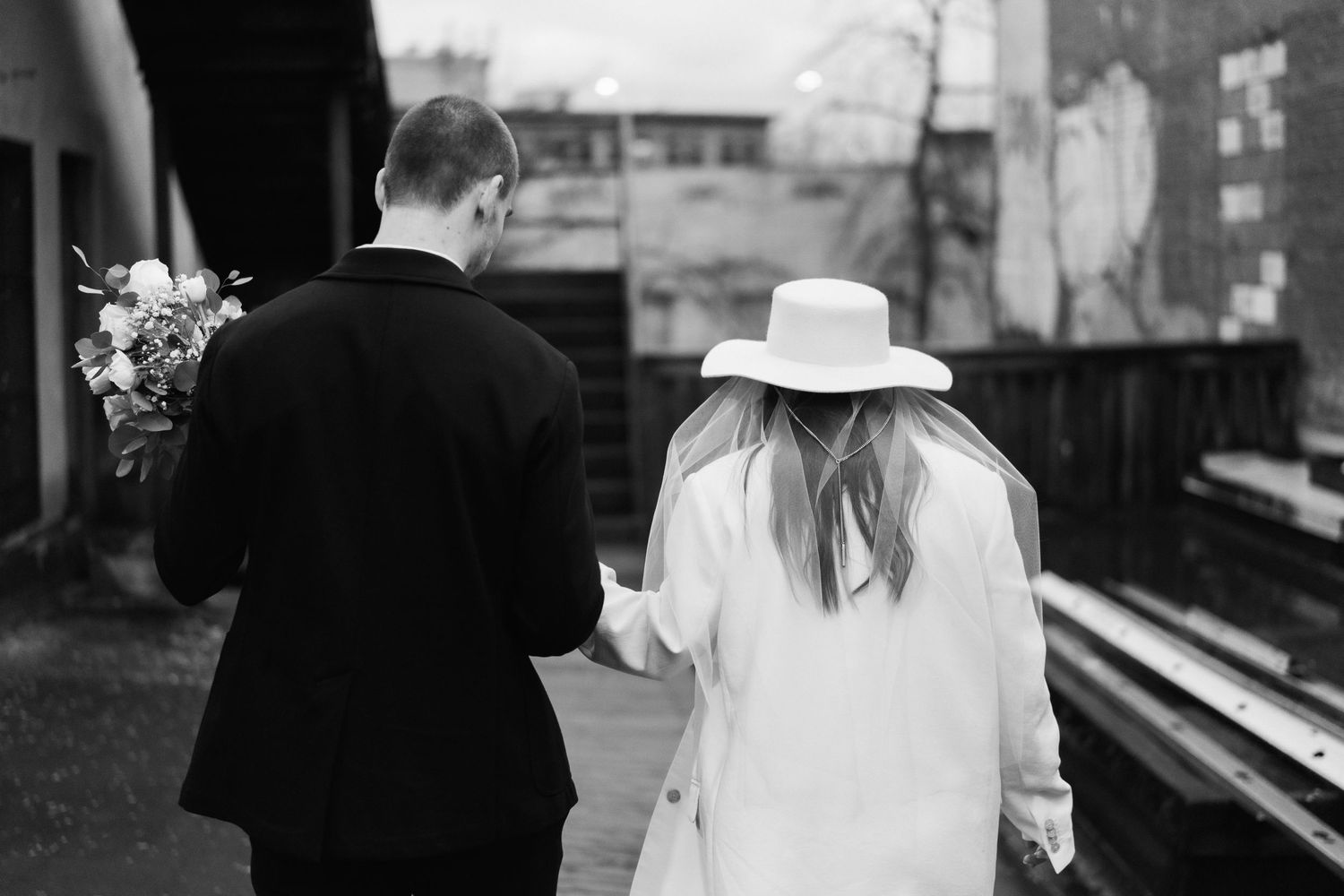 Black and white wedding photo showing couple from behind near a piano.
