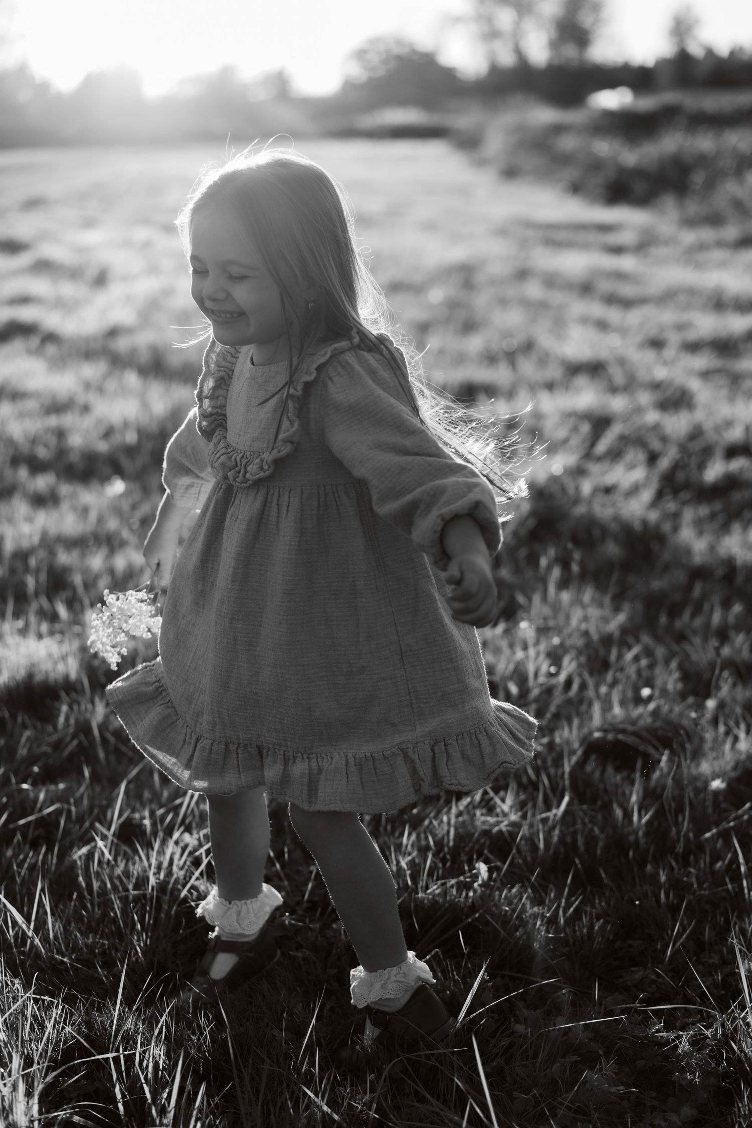 Silhouette of small child playing in grass during sunset.