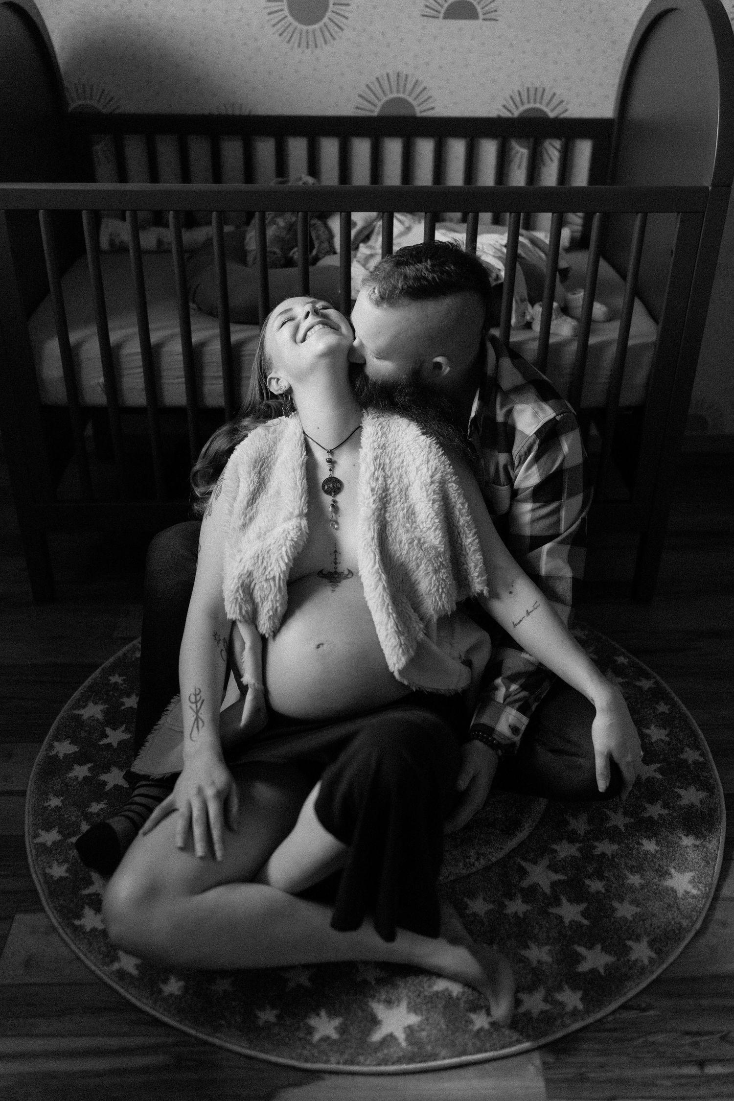 Close-up black and white sequence showing two figures hugging on a patterned rug in an intimate setting.