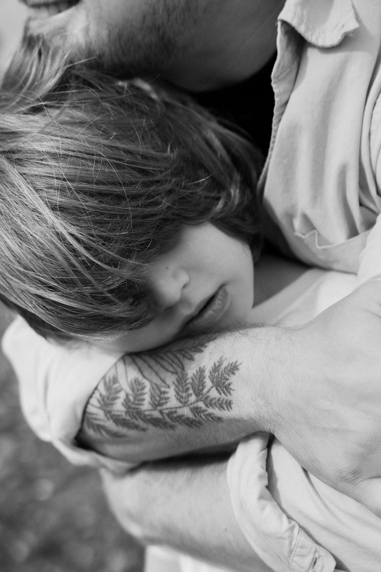 Close-up black and white shots showing gentle interactions and a leaf tattoo detail.