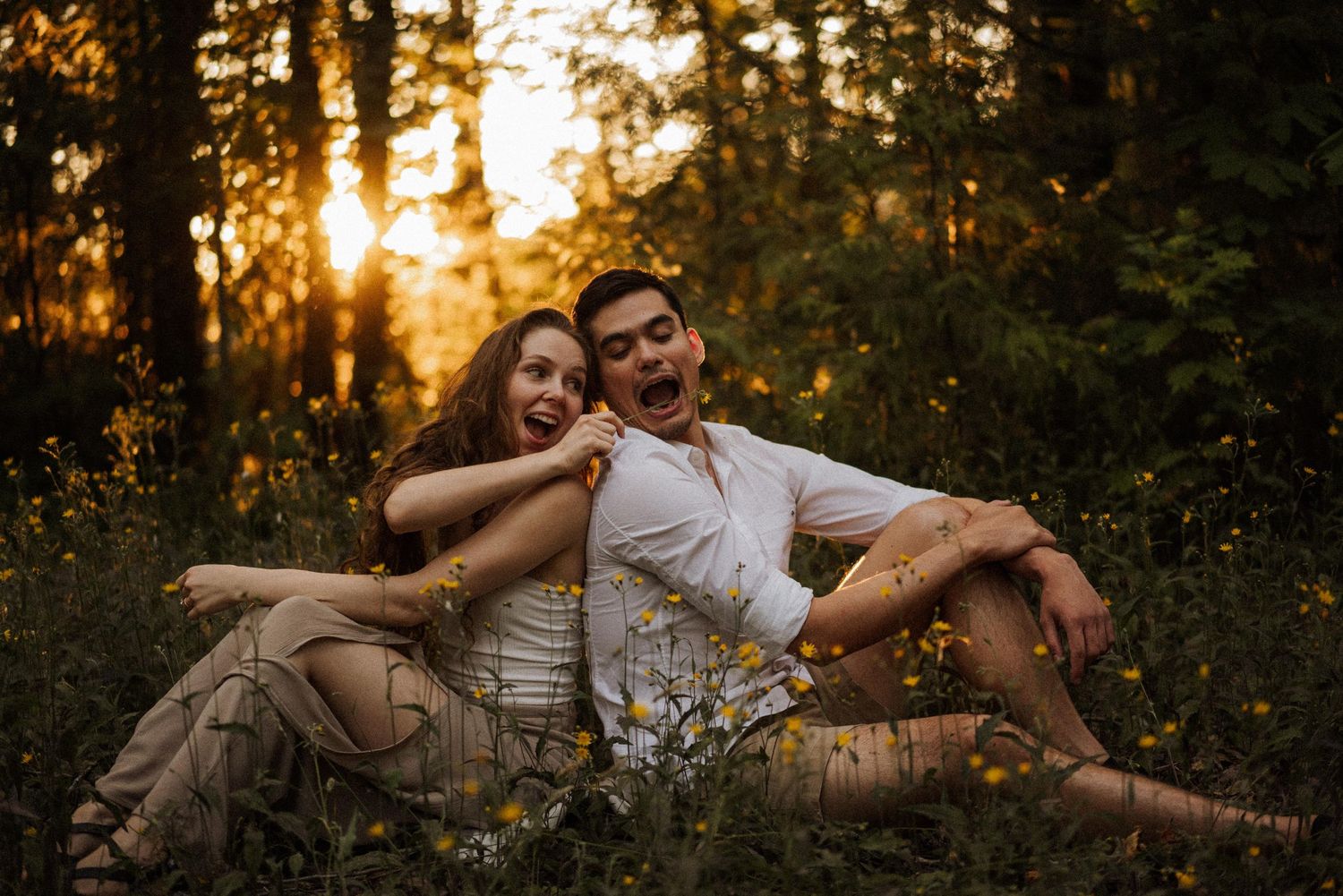 Couple shares playful moments on the forest floor during sunset.