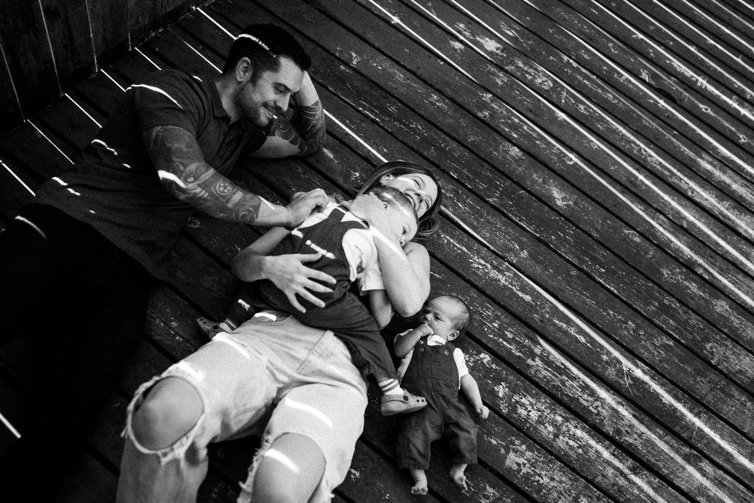A sequence of black and white photographs showing two people dancing together in an intimate embrace on wooden decking.
