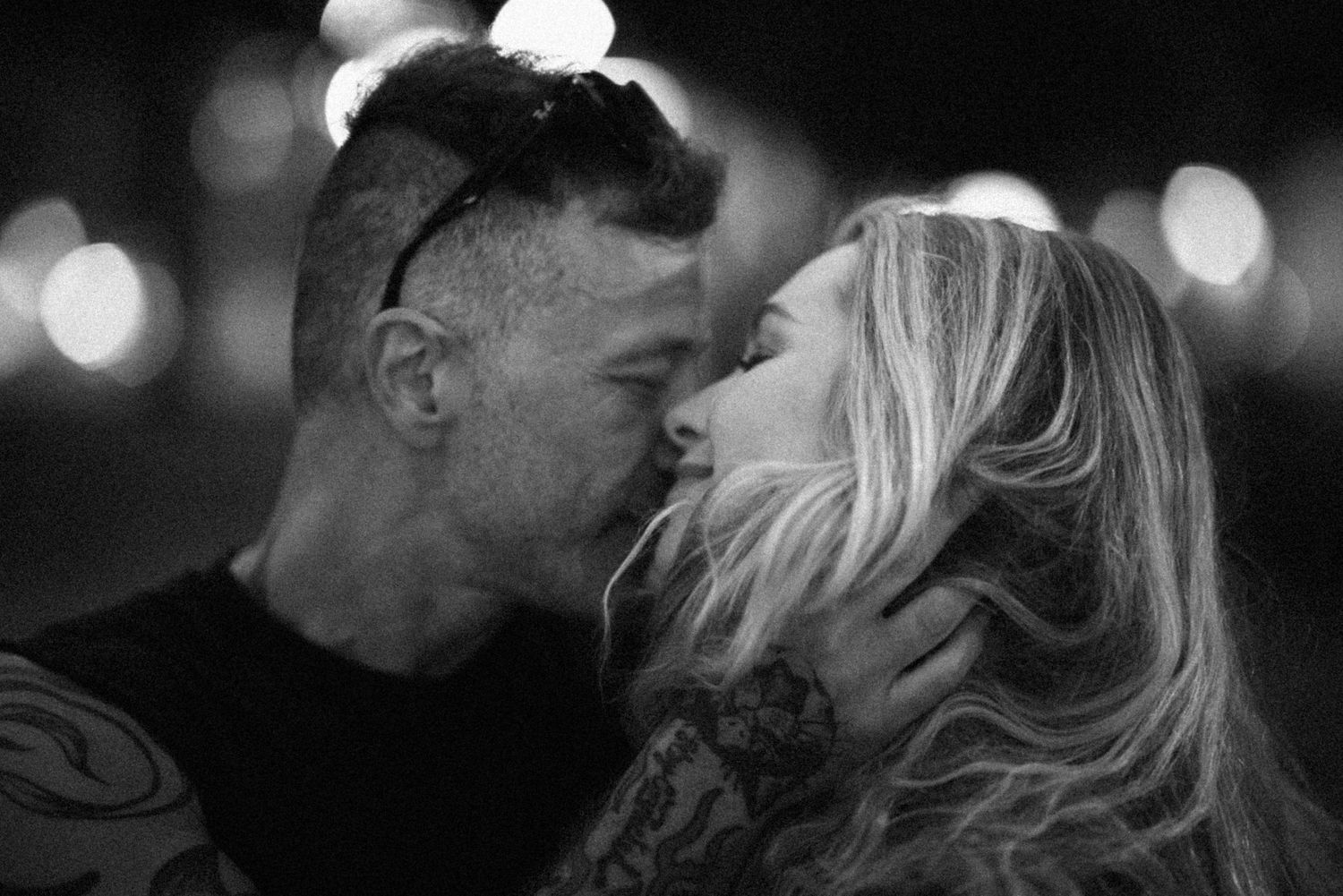 A series of black and white romantic photos showing intimate moments between couples with blurred bokeh lights in background.