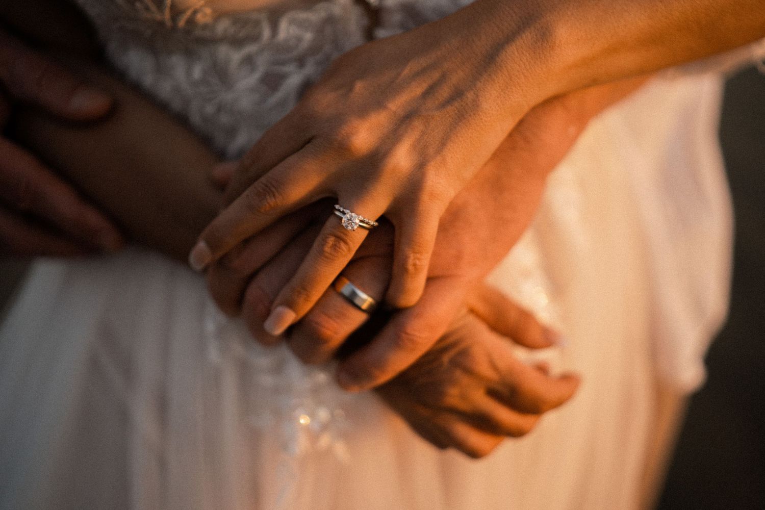 Soft focus close-up of hands with wedding ring in warm lighting.