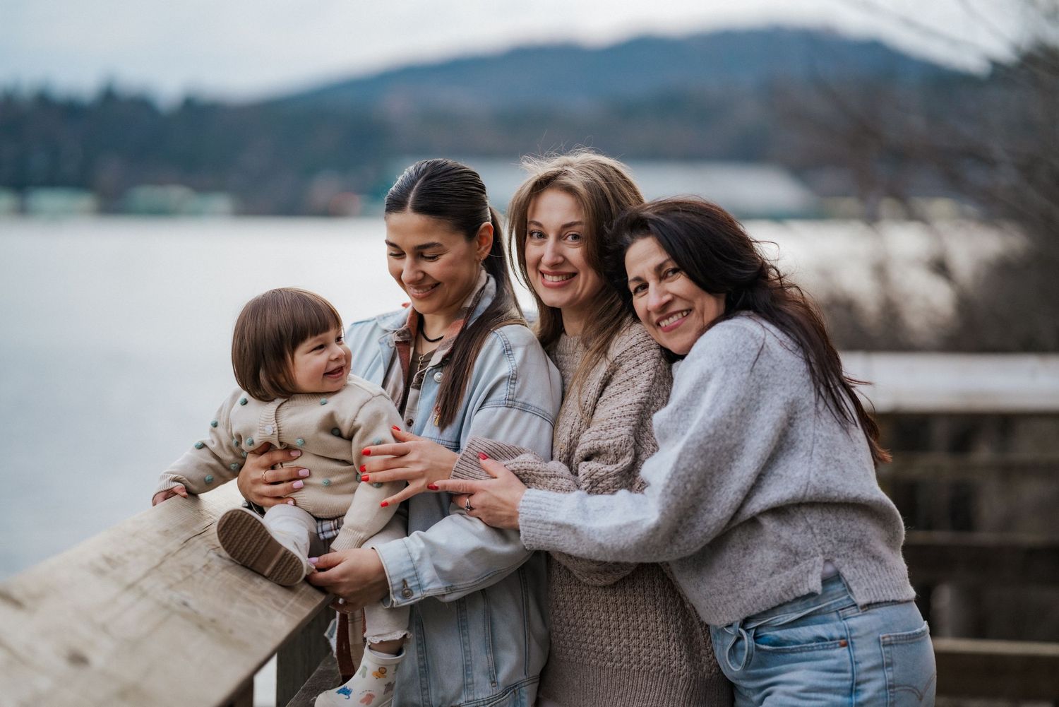 A cheerful group shares a moment together by a lakeside on an overcast day.