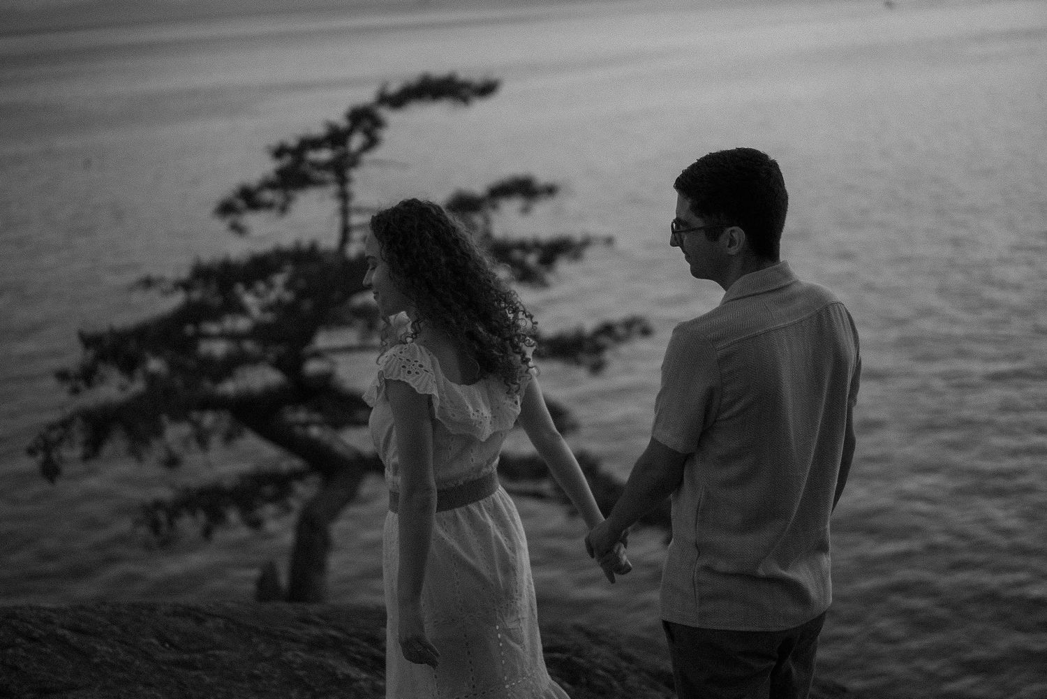 Silhouettes against ocean backdrop during sunset on coastal cliffs.