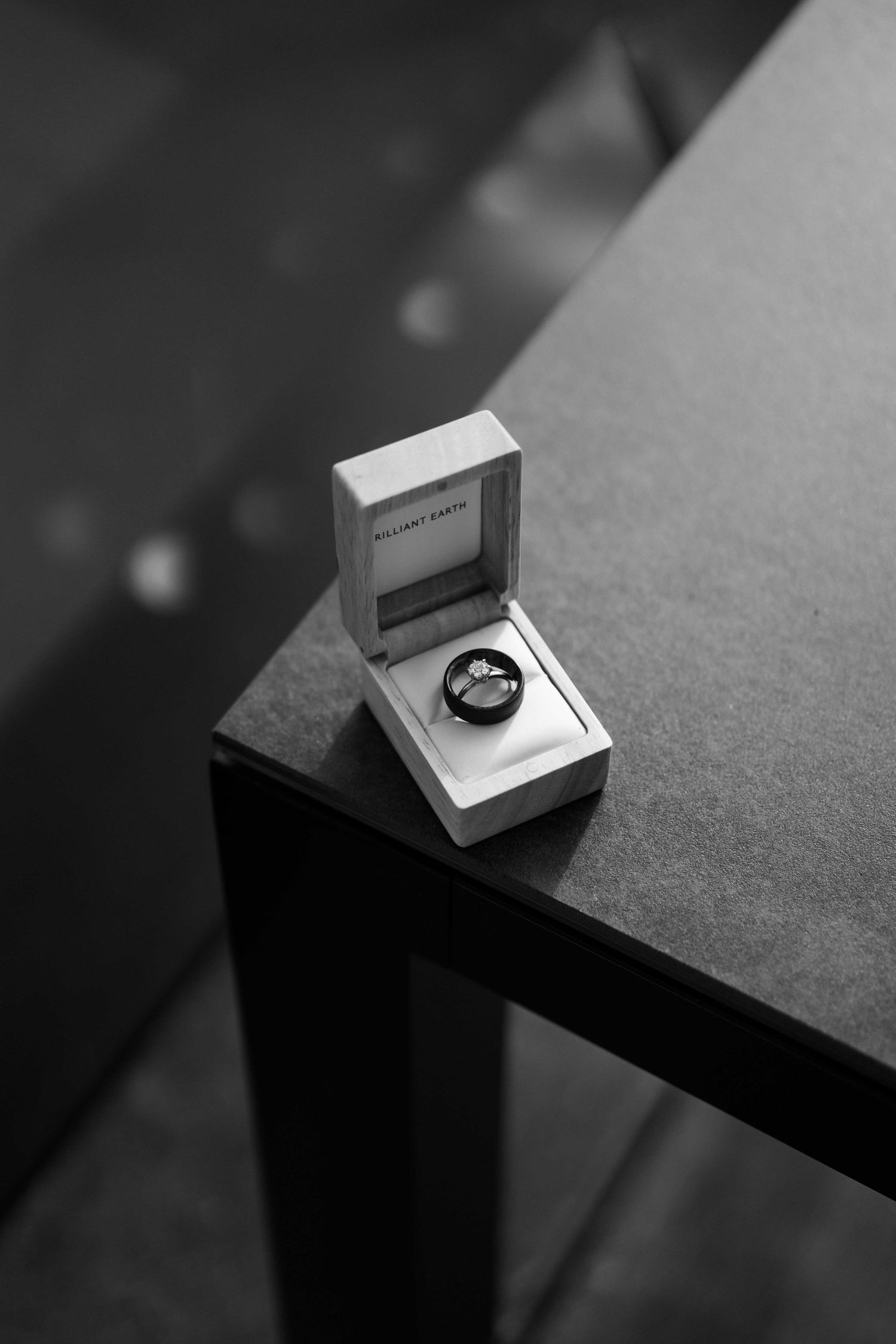 Wedding ring box displayed on dark surface in black and white photography.