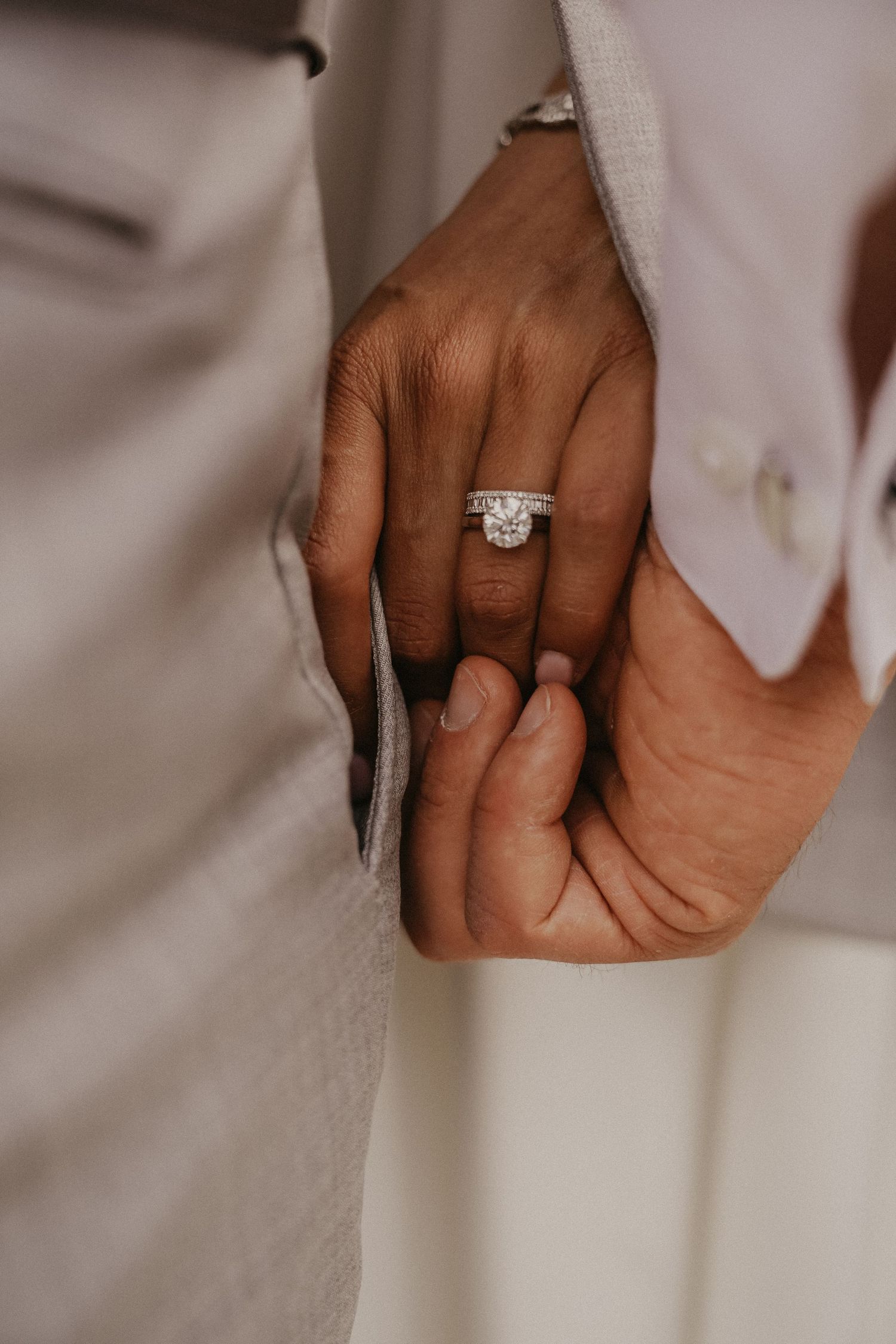 Close-up shot of intertwined hands with sparkling diamond engagement ring.