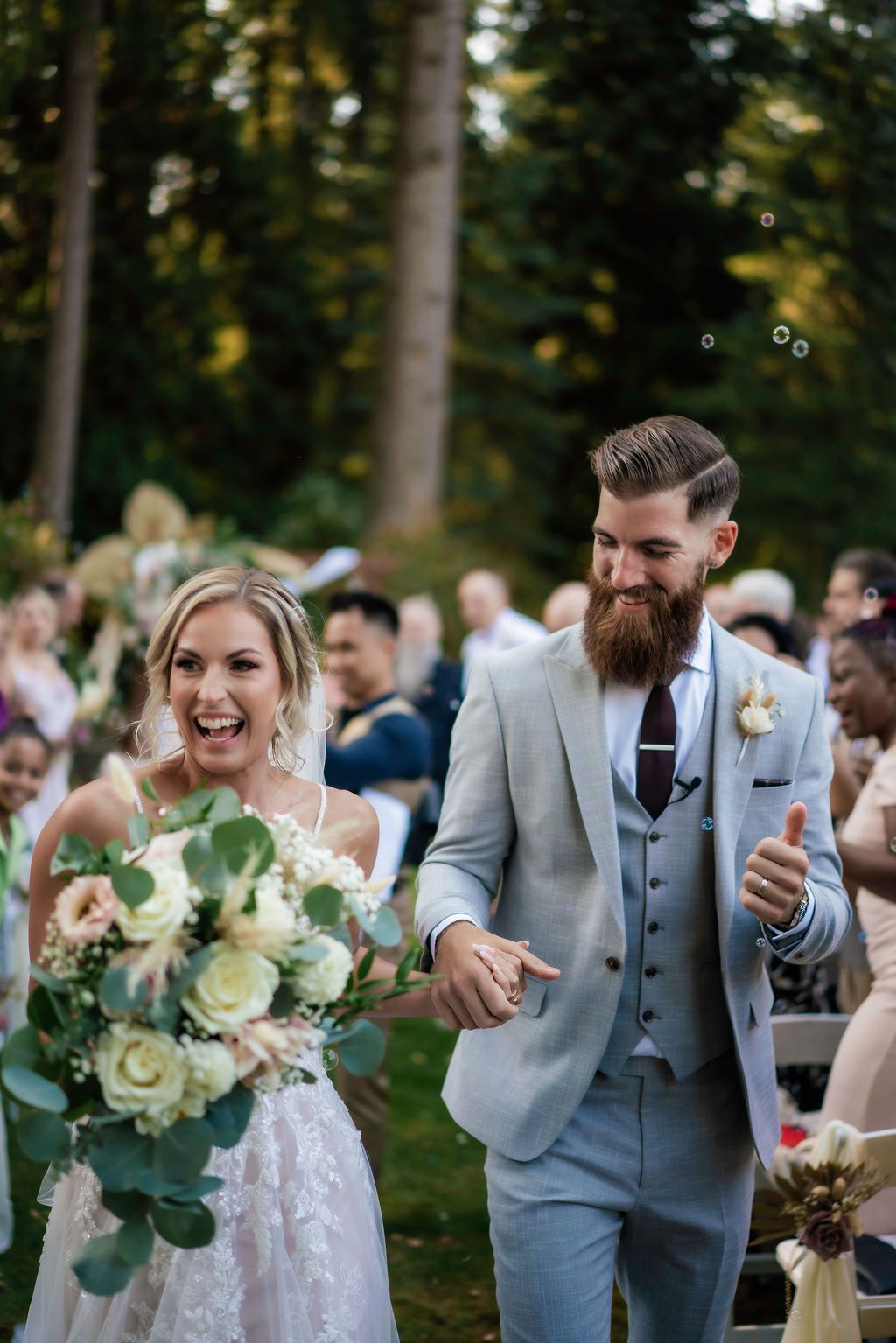 Joyful wedding celebration outdoors with elegant floral bouquets and grey suits.