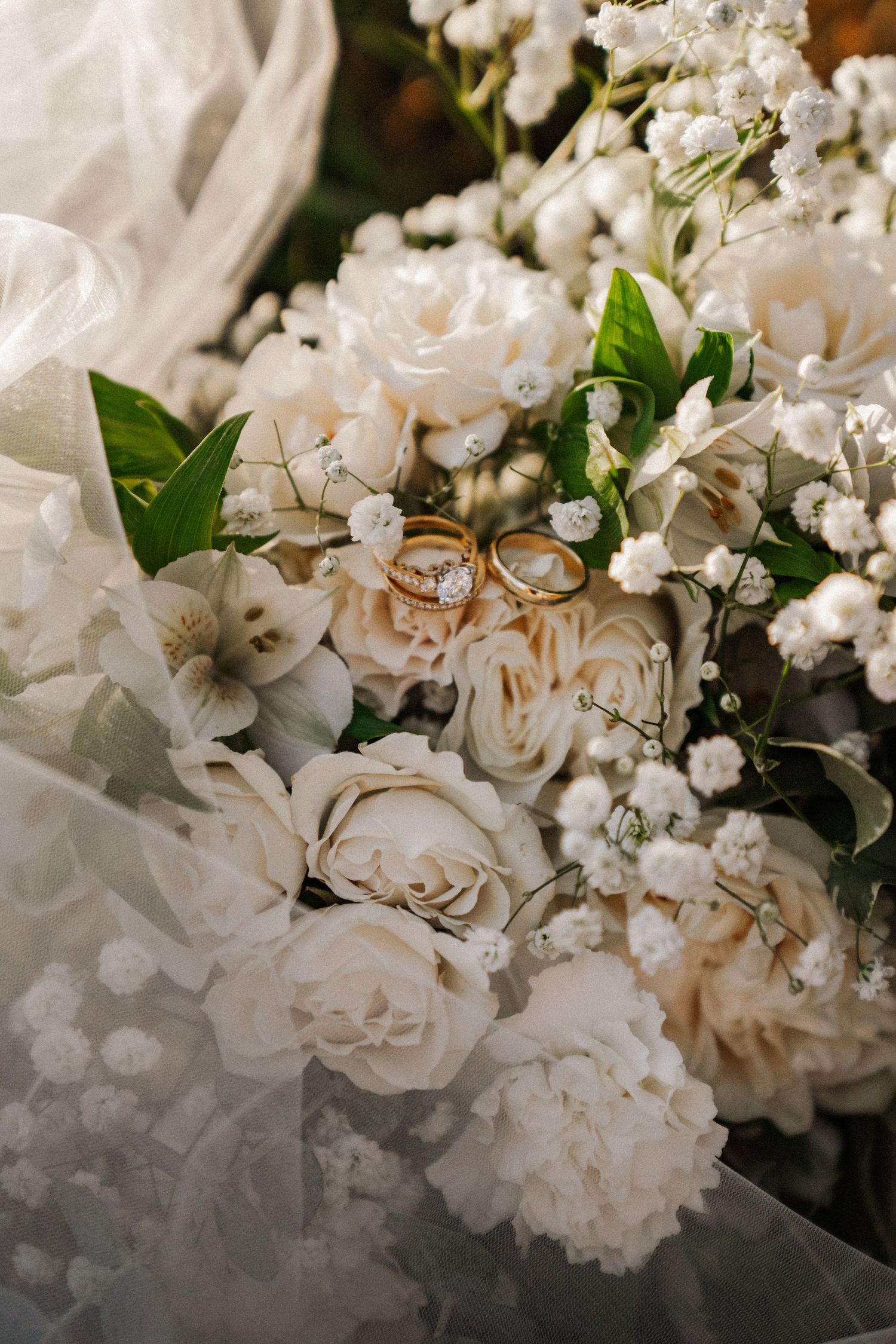 Delicate white roses and baby's breath flowers arranged with green foliage create an elegant wedding bouquet display.