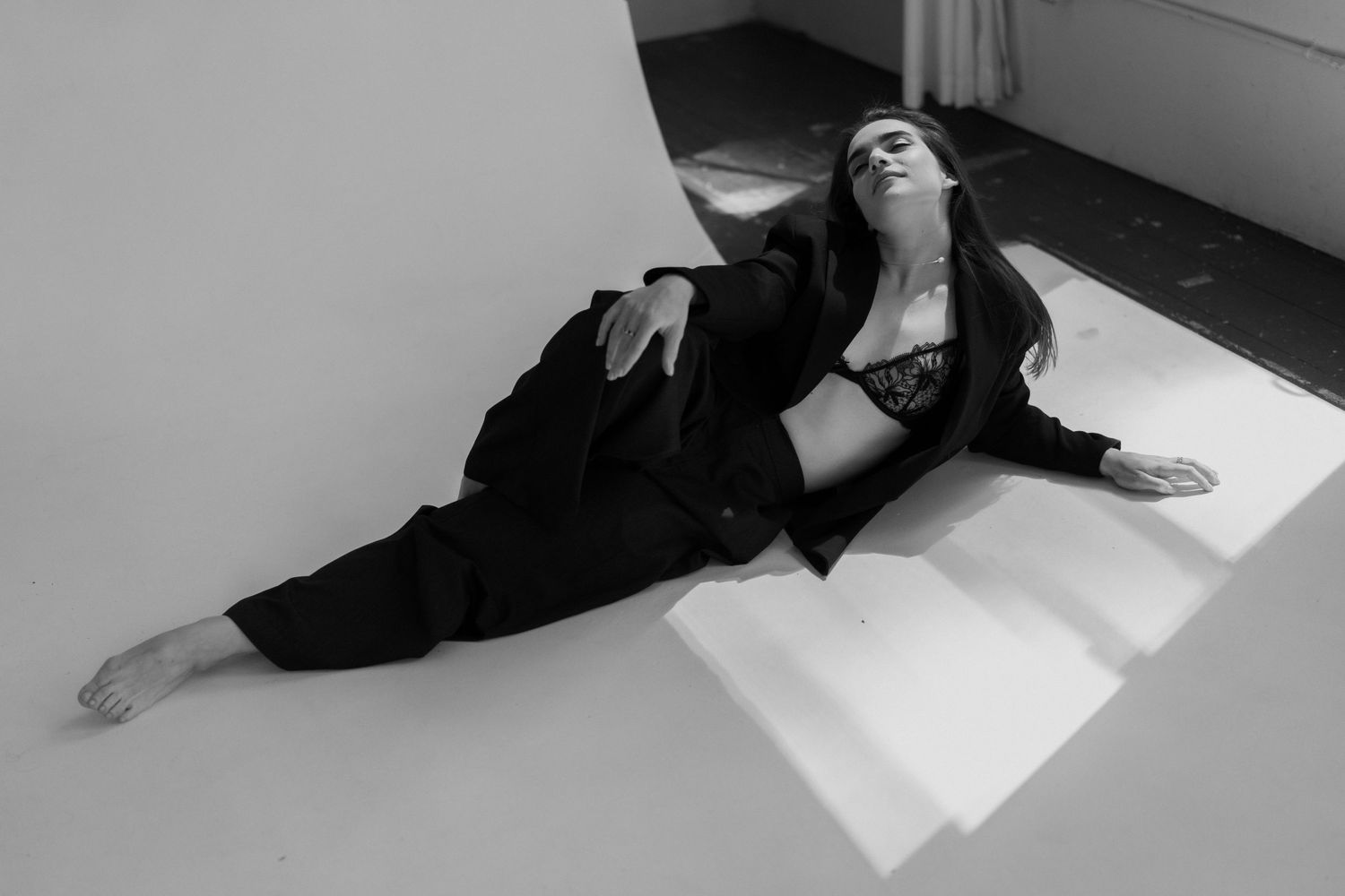 Artistic black and white composition of reclining figure in window light.