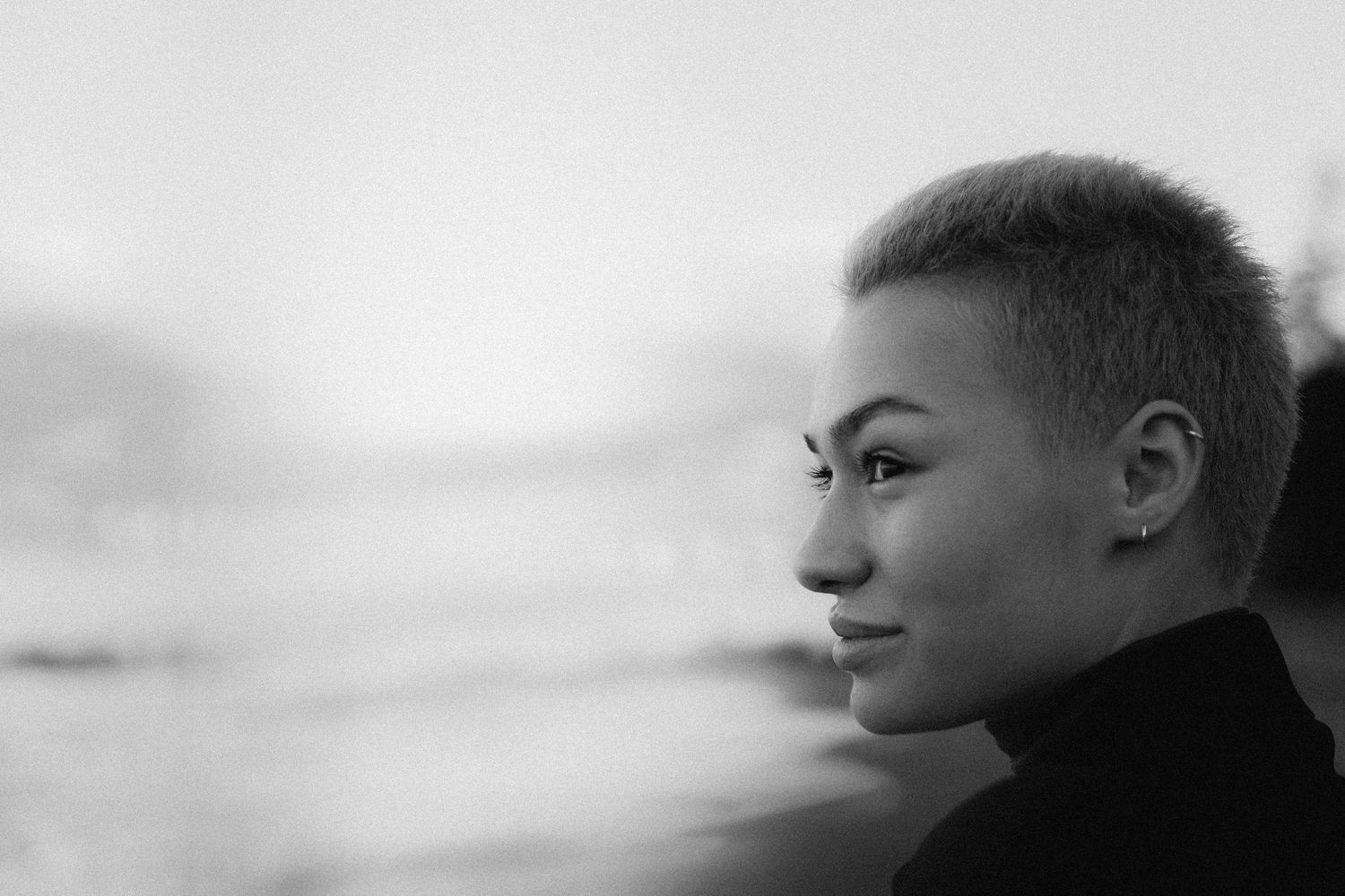 Black and white profile portrait showing a person with short hair looking pensively into the distance.