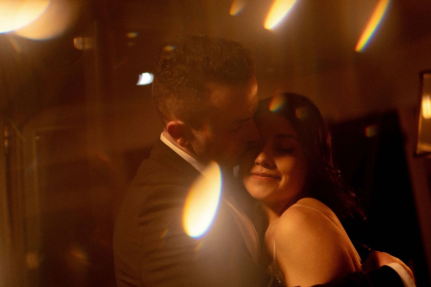 Romantic wedding moment captured in warm amber lighting during an evening celebration.