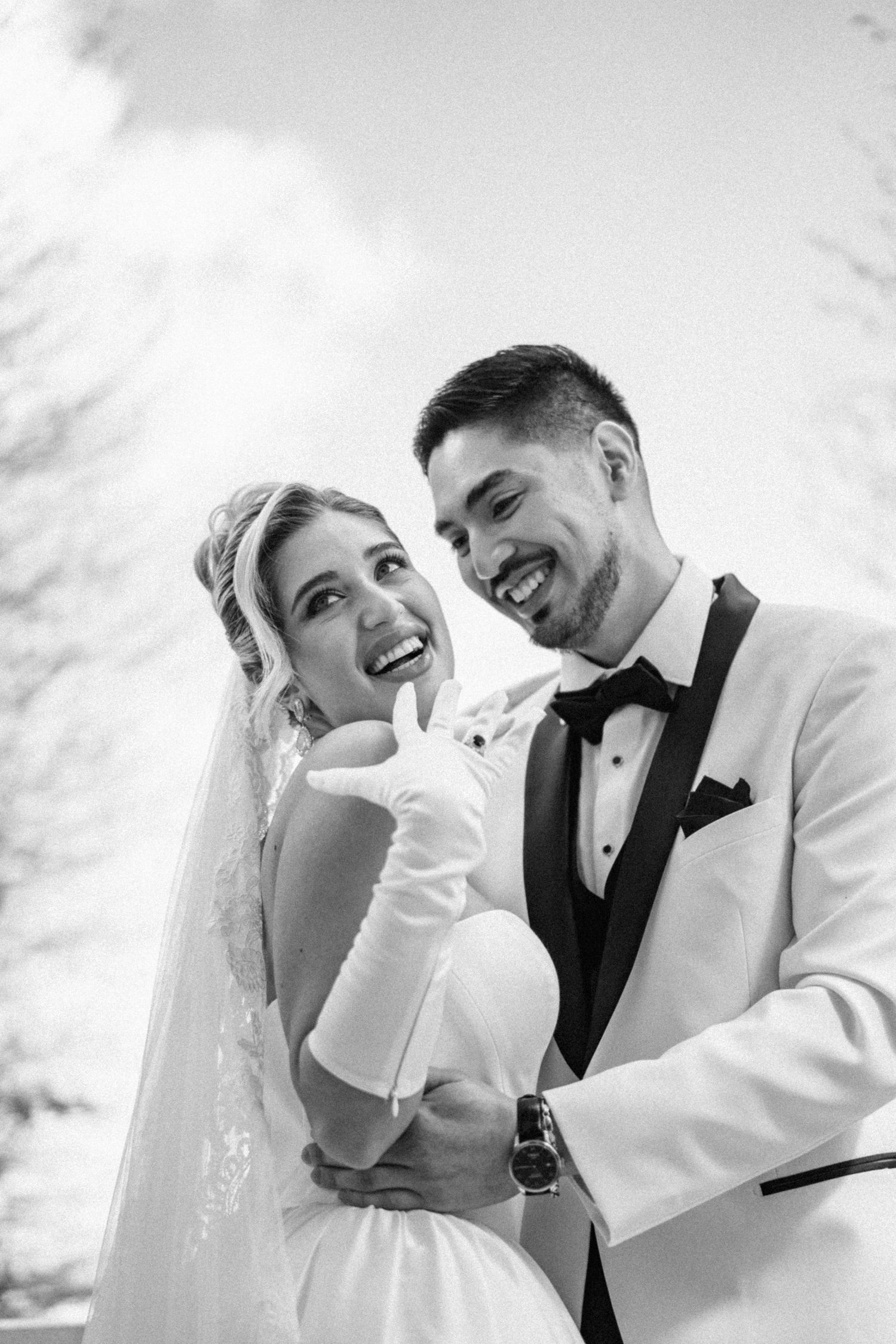 Romantic black and white portrait of newlyweds sharing an intimate moment in formal wedding attire.