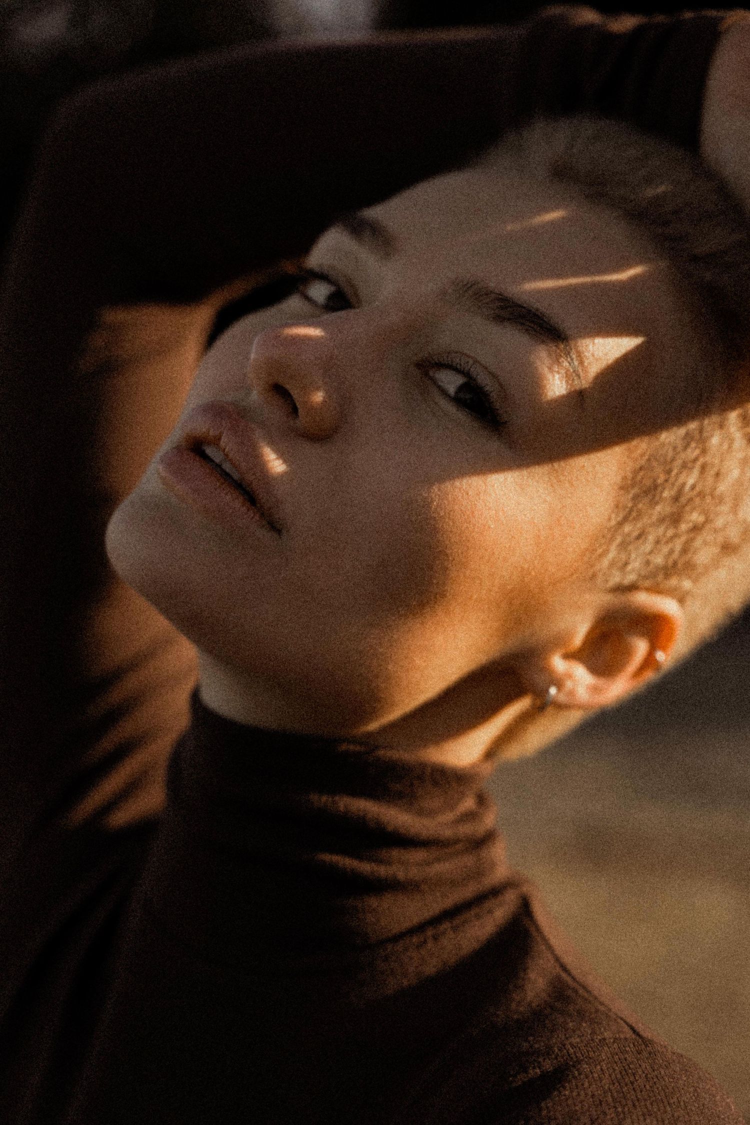 A dramatic series of portrait shots showing a person in moody lighting wearing a dark turtleneck sweater.