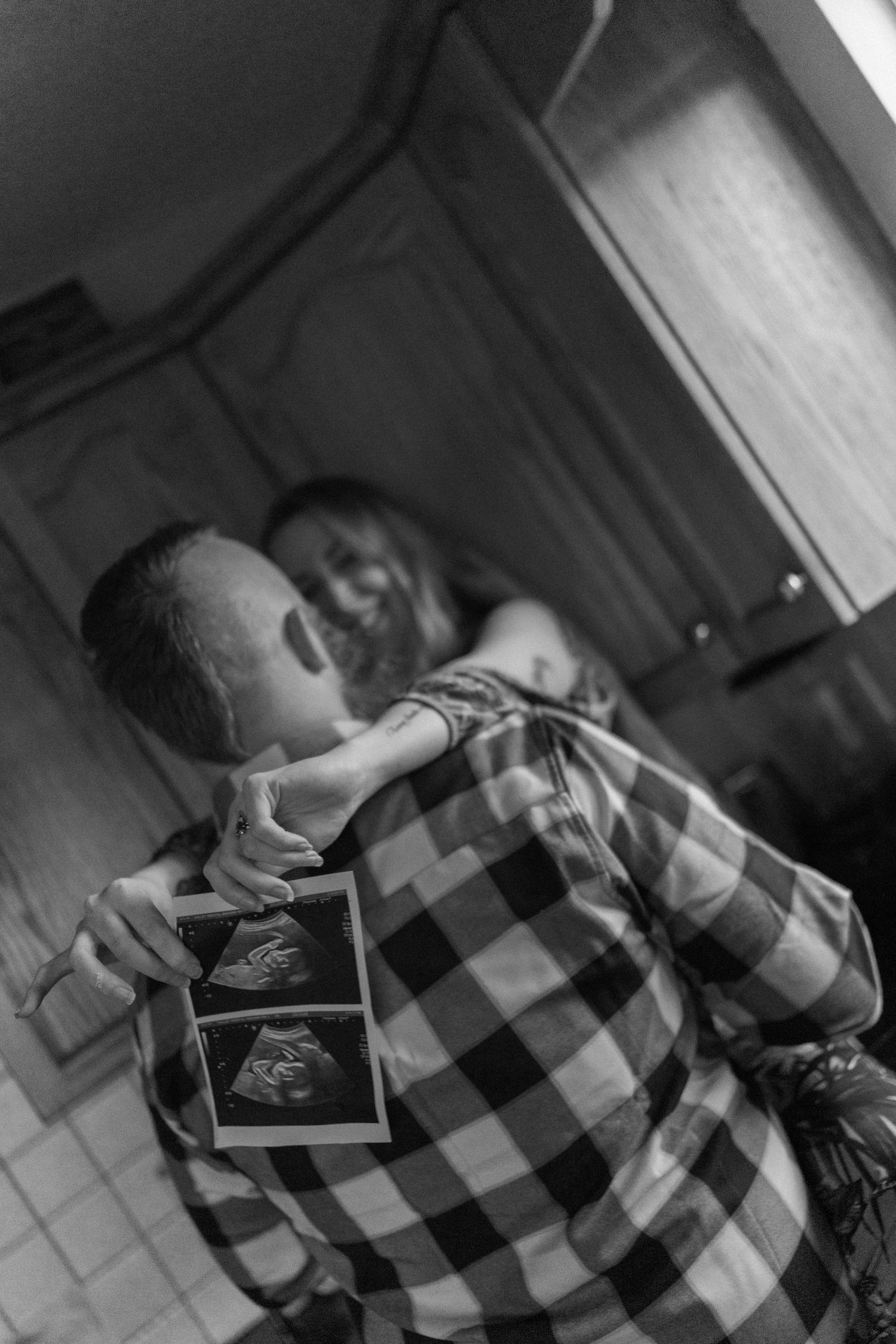 Intimate black and white sequence showing figures sharing tender moments with a checkered pattern visible.