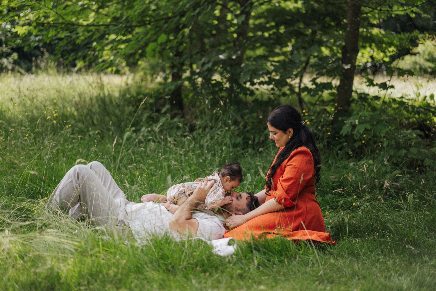 Family relaxing together on a blanket in a peaceful garden setting.