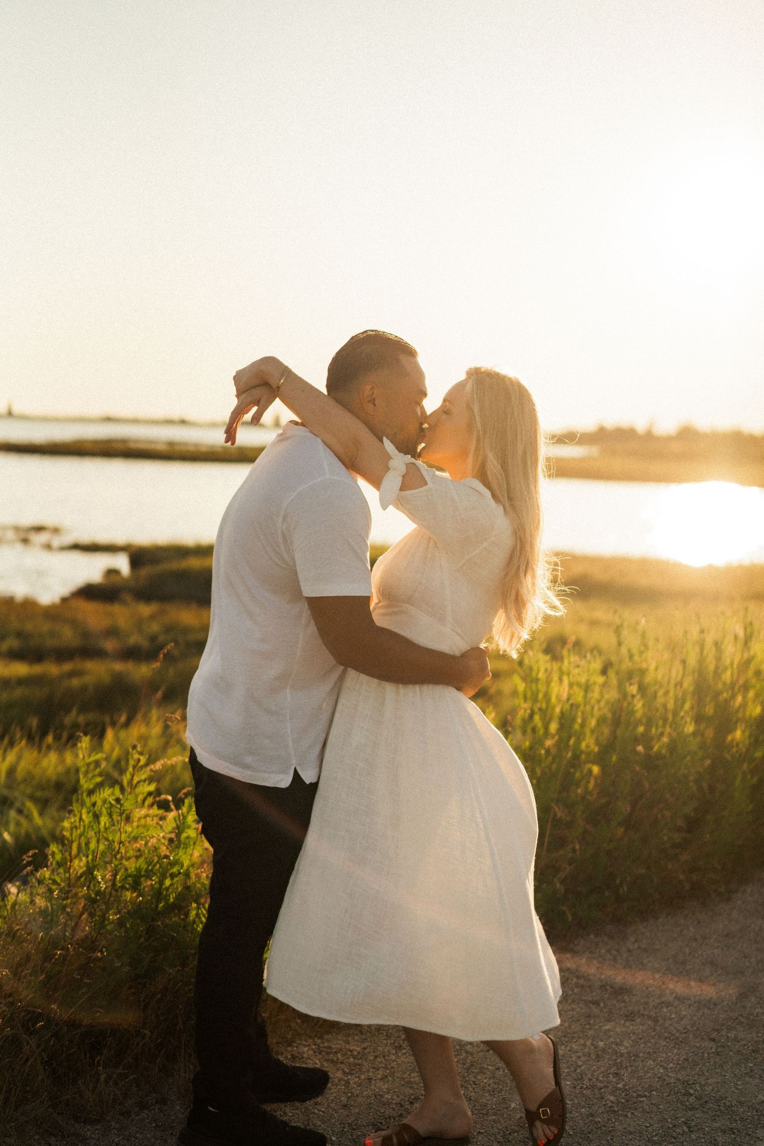 A couple dances together on a coastal path during sunset.