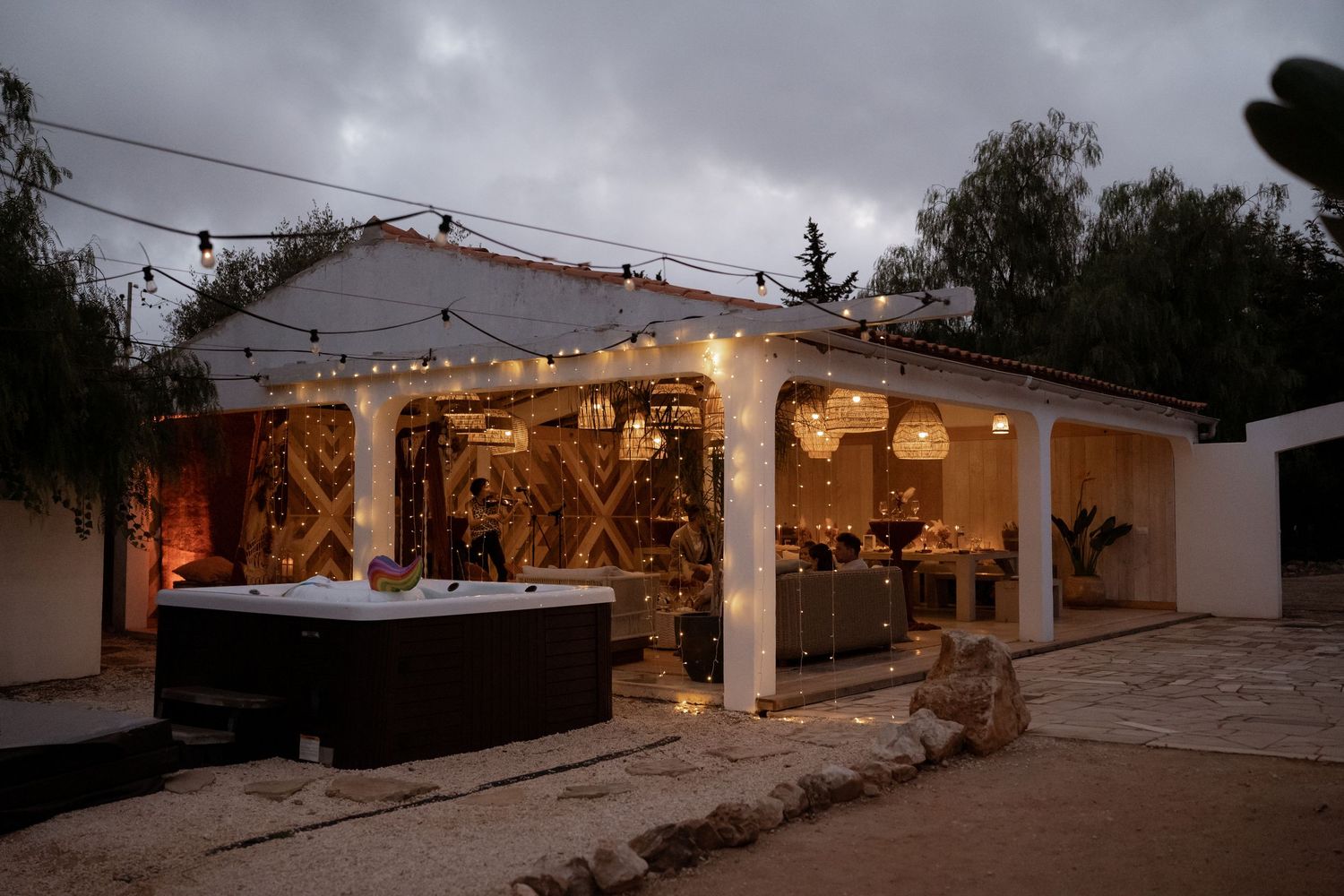 Cozy outdoor patio with string lights, hot tub, and barn doors at dusk creating a warm ambiance.