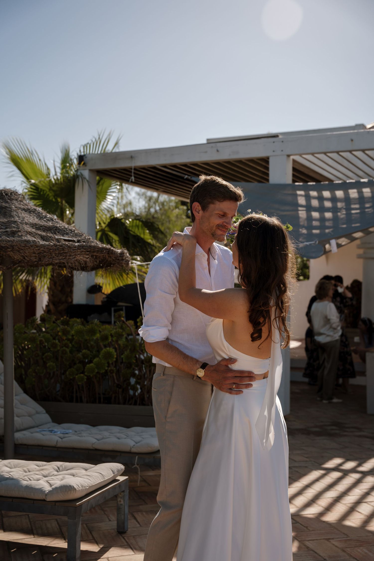 Bride and groom share a romantic first dance outdoors at a sunny beach wedding.