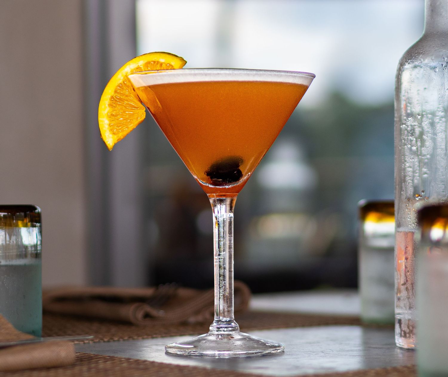 Elegant orange martini cocktail with cherry and orange slice garnish in a stemmed martini glass.