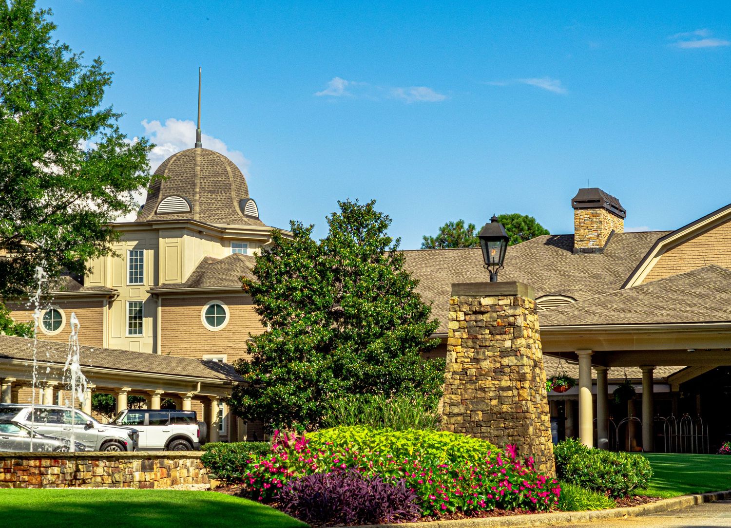 Grand hotel entrance with manicured gardens, stone pillars, and a distinctive domed roof.