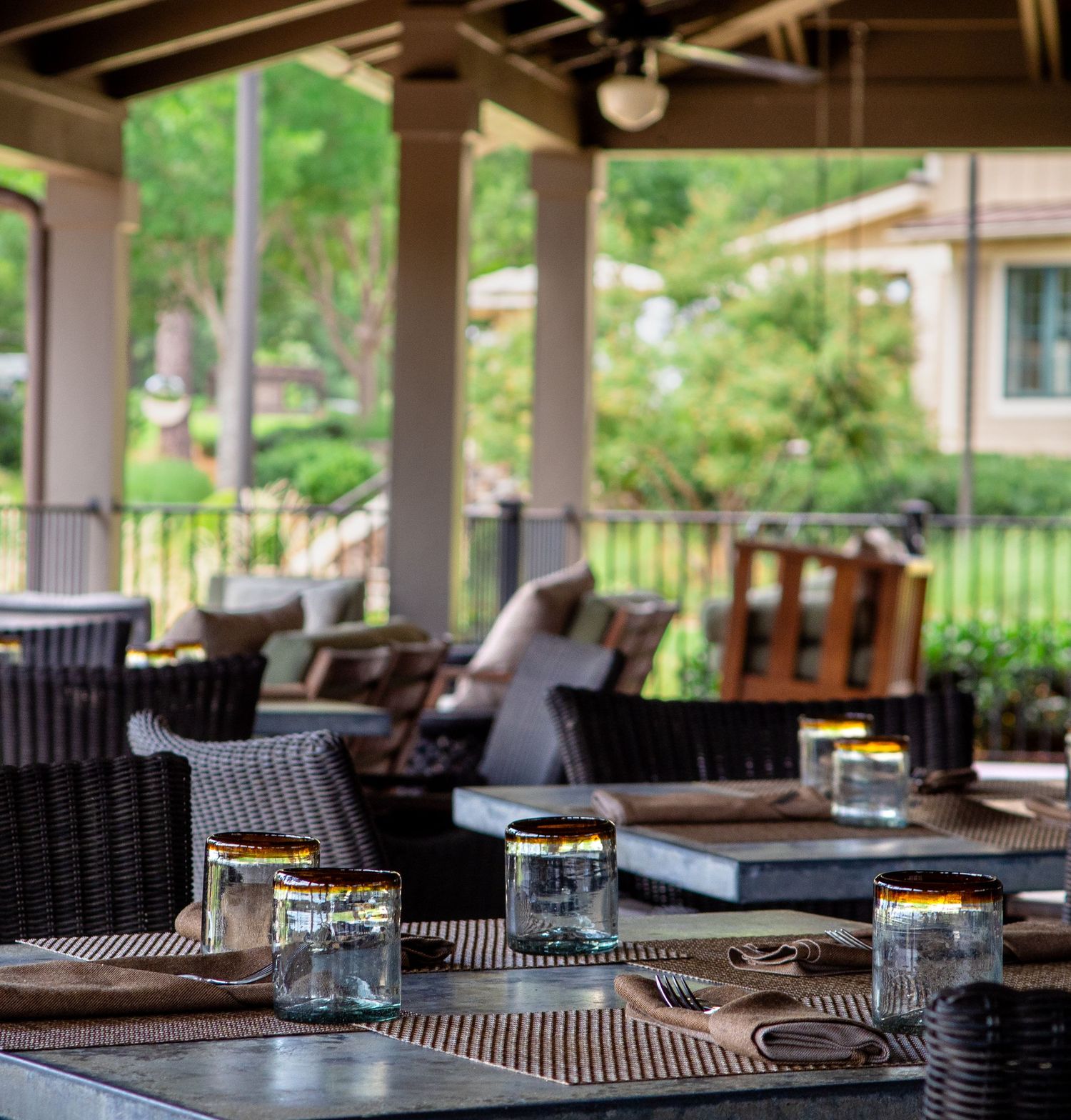 Dining patio with wicker chairs, decorative jar candles, and verdant garden scenery. Luxury hospitality photographer