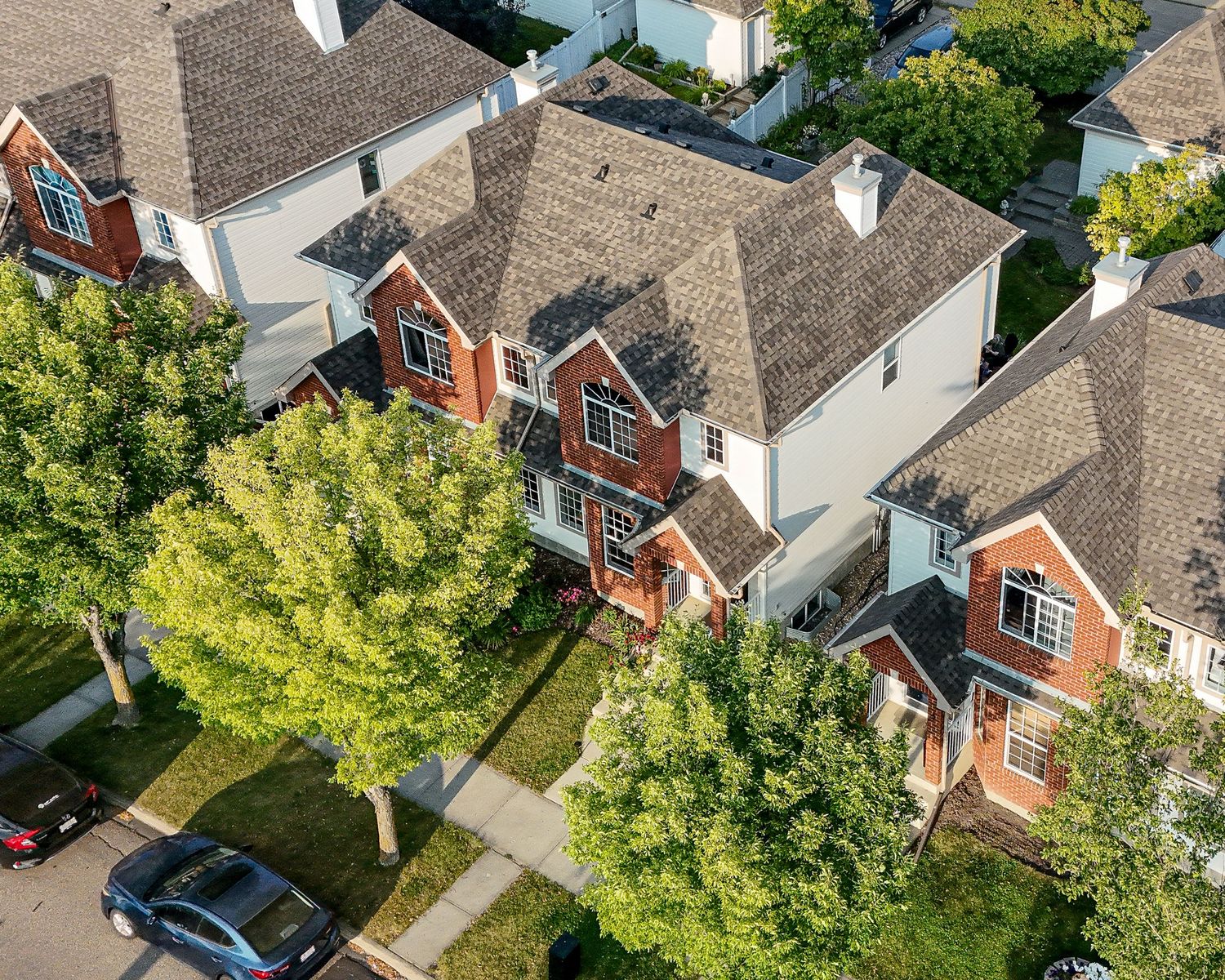 Central Alberta Real Estate Media David Spence Photography  Drone areial image of a brick faced duplex along a treed roadway - Spence Media