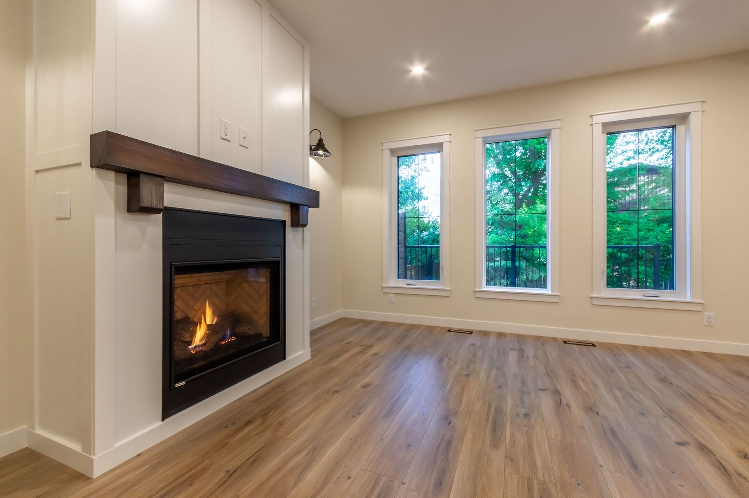 Central Alberta Real Estate Media David Spence Photography cozy living room and a crackling fireplace and tall windows looking onto backyard