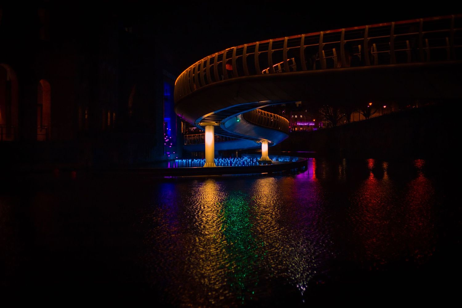 Illuminated bridge at Light Up Bristol festival with colourful reflections on the water.