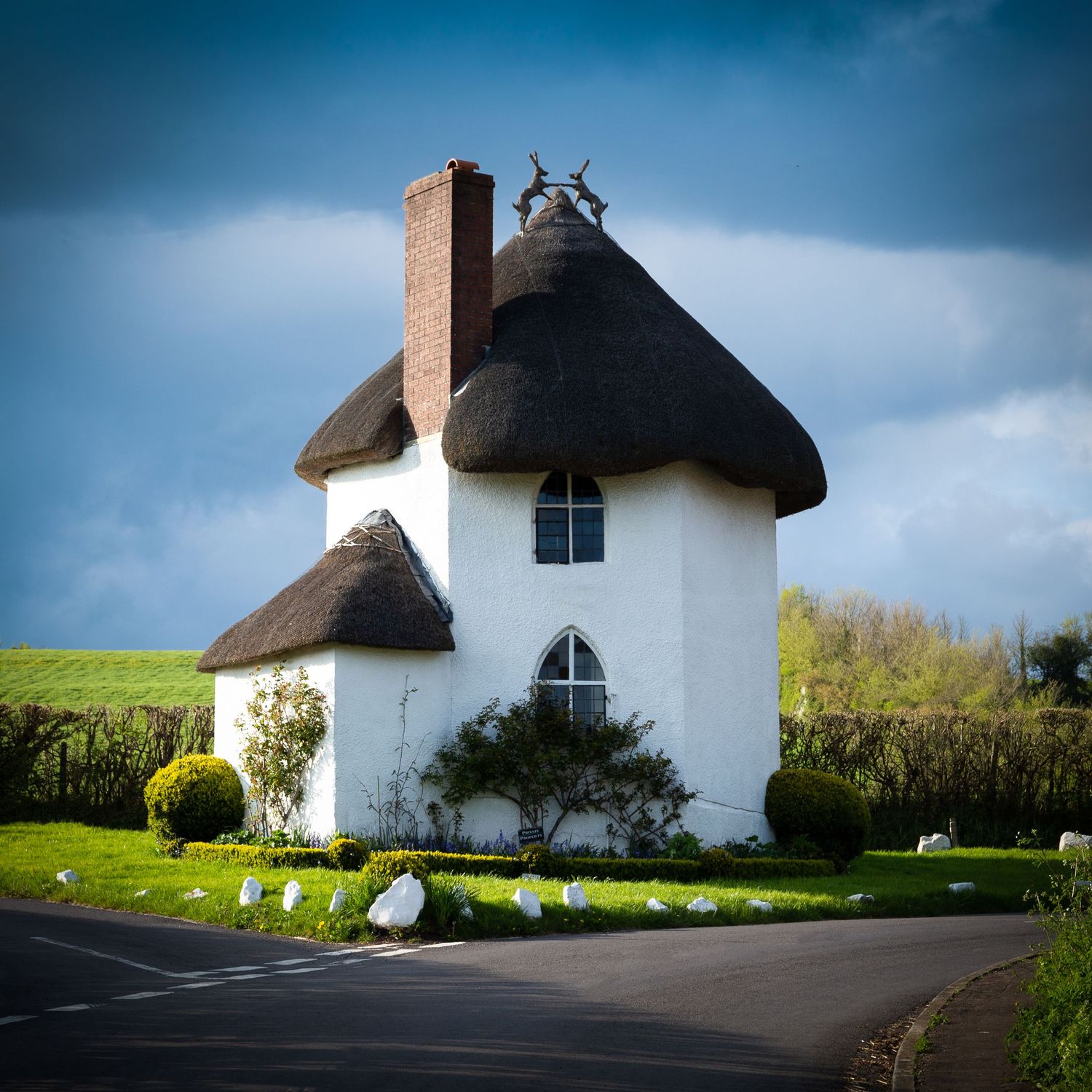 Thatched cottage in rural England with blue sky and garden in front. The Roundhouse, Stanton Drew