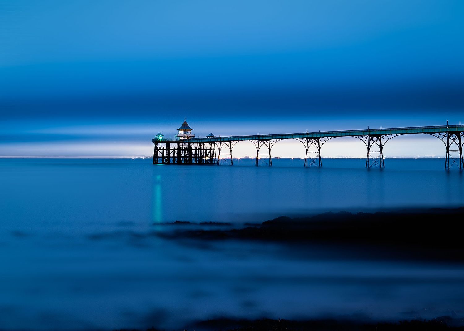 Clevedon Pier in Somerset photographed at blue hour with reflection on the water.