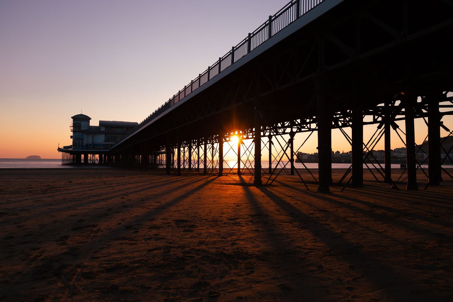 Weston-super-Mare Grand Pier at sunset with long shadows across the beach, Somerset coast.