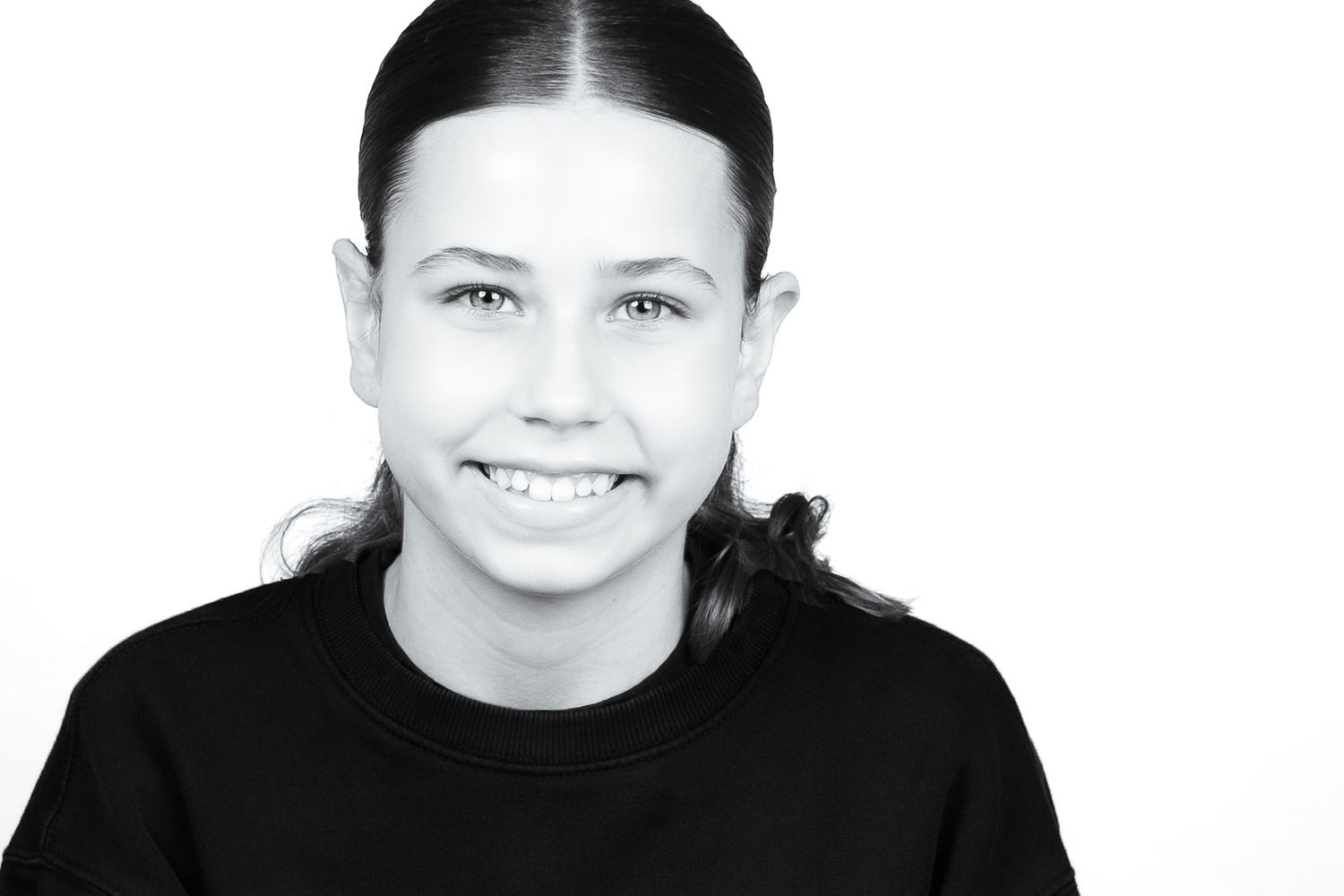 Studio headshot of a smiling girl in a black top against a white background in Southwest UK.