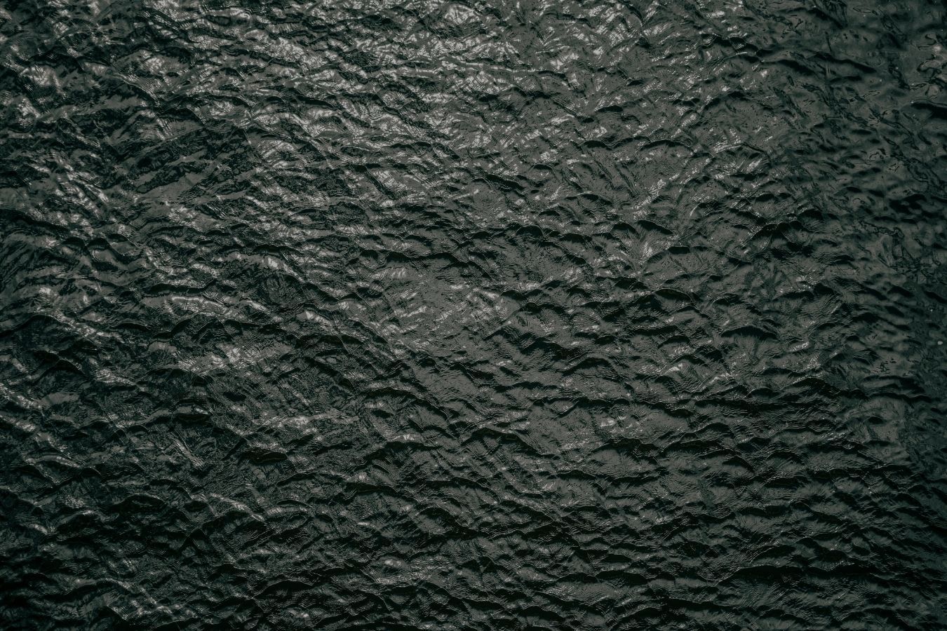 Dark textured black stone or slate surface background with rough uneven pattern and subtle details.