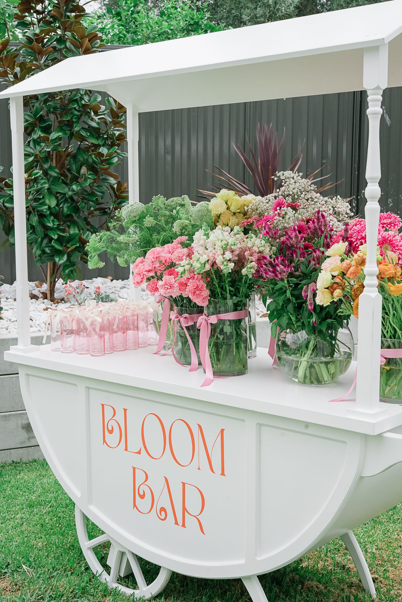 White bloom bar cart decorated with pink and peach flower arrangements in the garden.