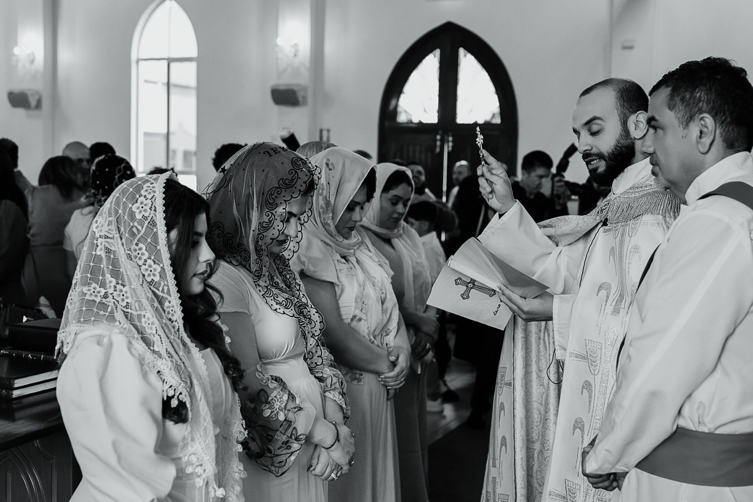 Religious ceremony in a church with participants wearing traditional white veils during a service.
